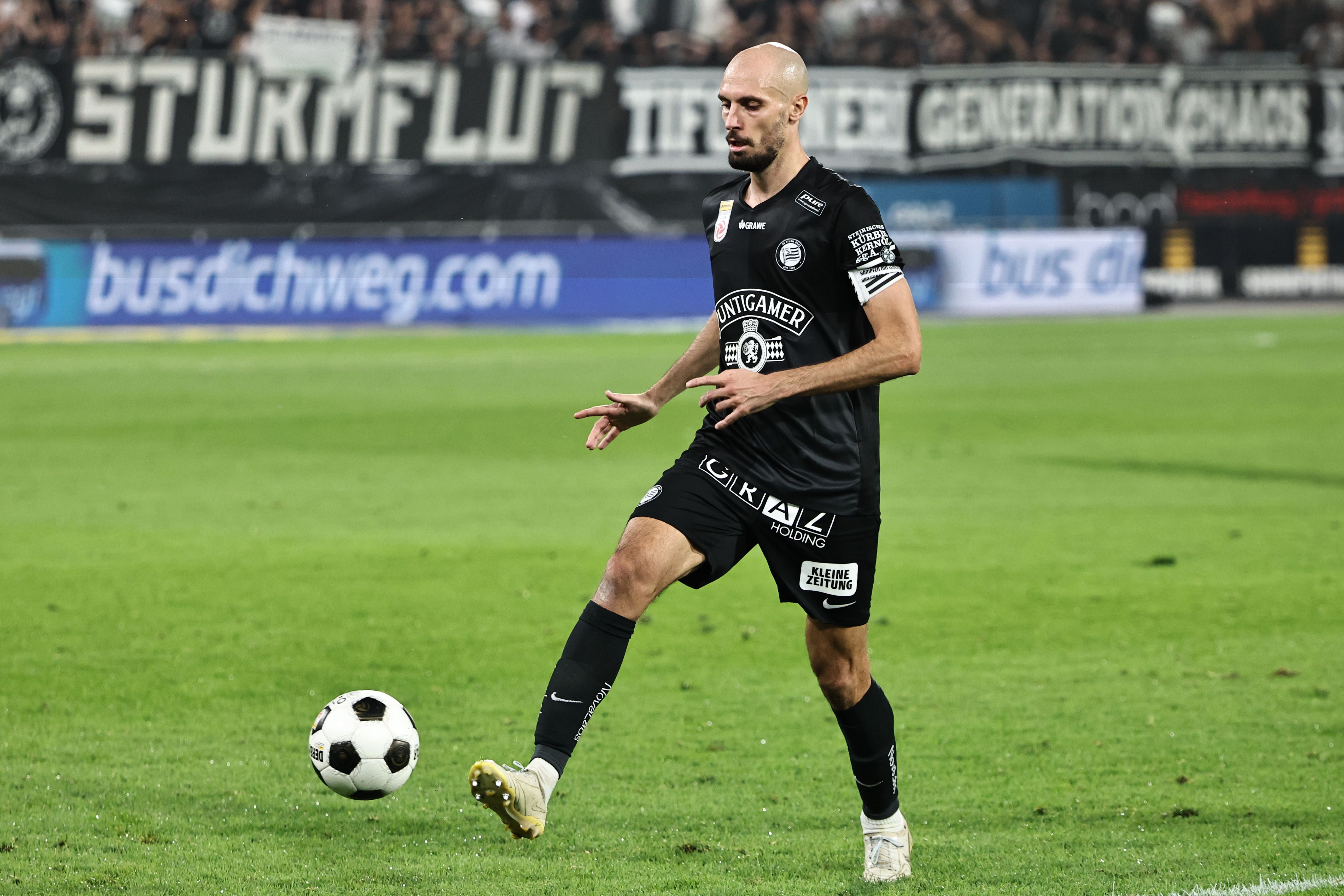 Ein Fußballspieler von Sturm Graz spielt den Ball während eines Spiels auf dem Rasenplatz.