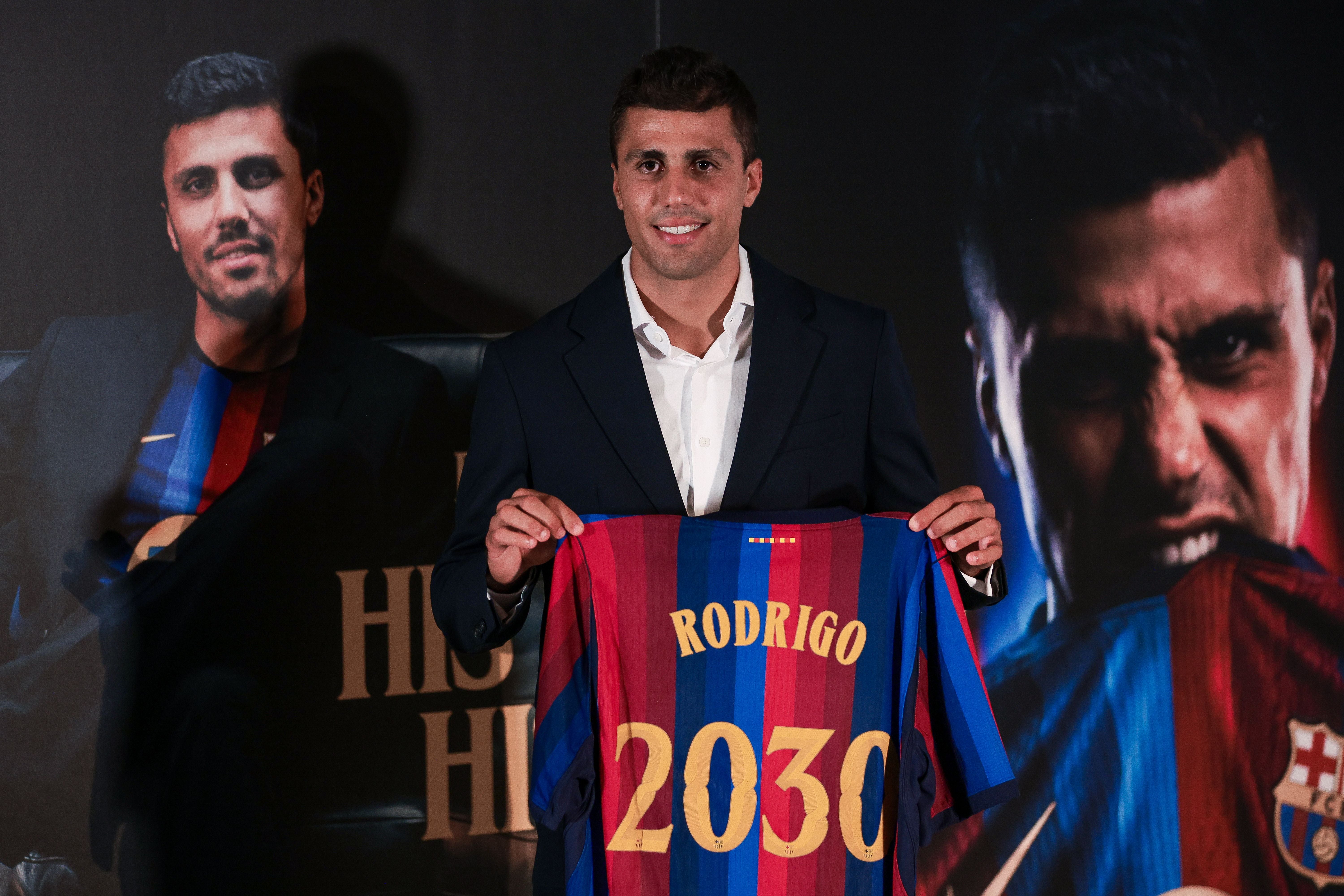 Rodri hält ein FC-Barcelona-Trikot mit dem Namen "Rodrigo" und der Nummer 2030 hoch.