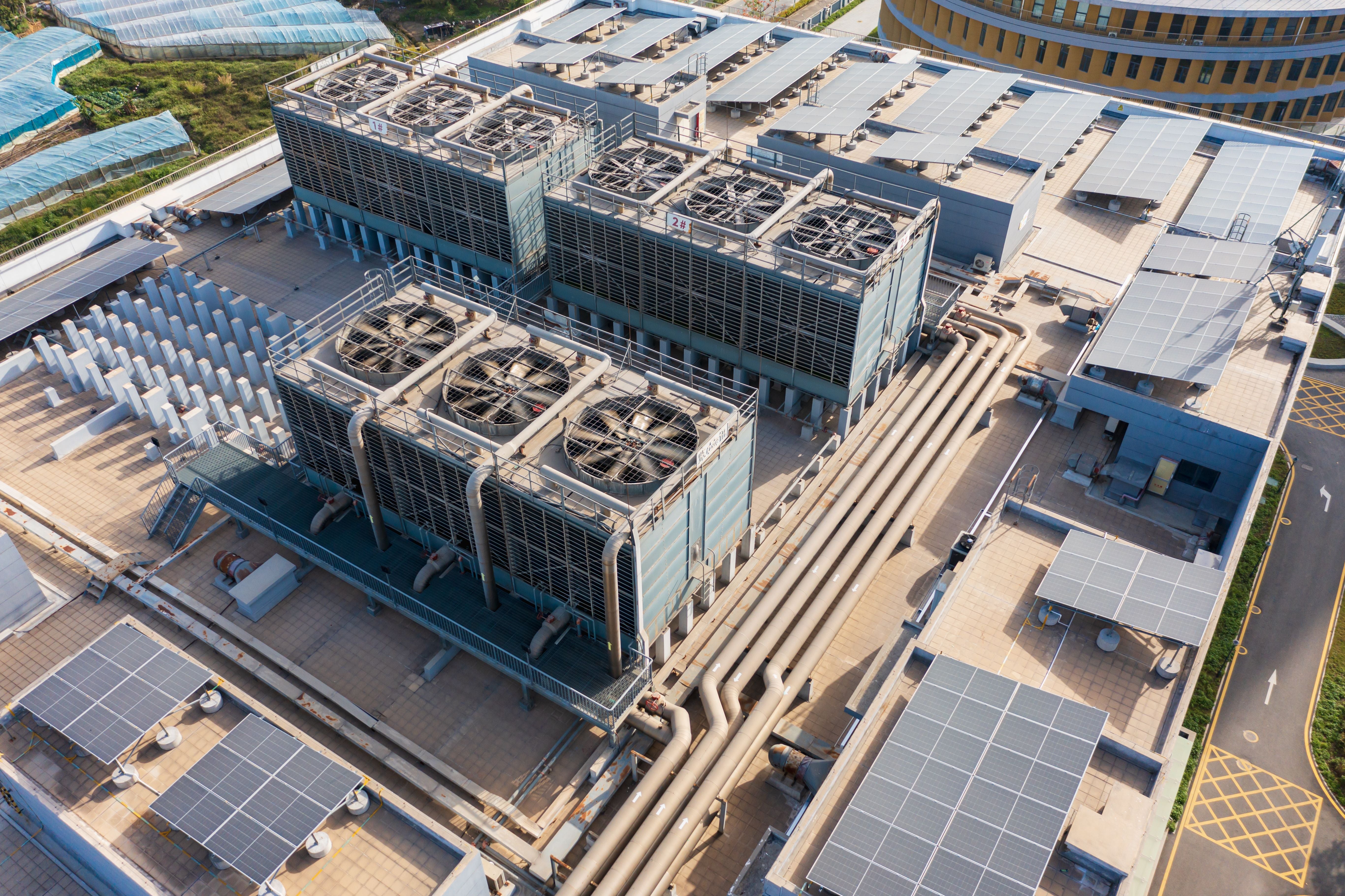 Luftaufnahme einer großen Industrieanlage mit Kühlaggregaten und Solarpanelen auf dem Dach.