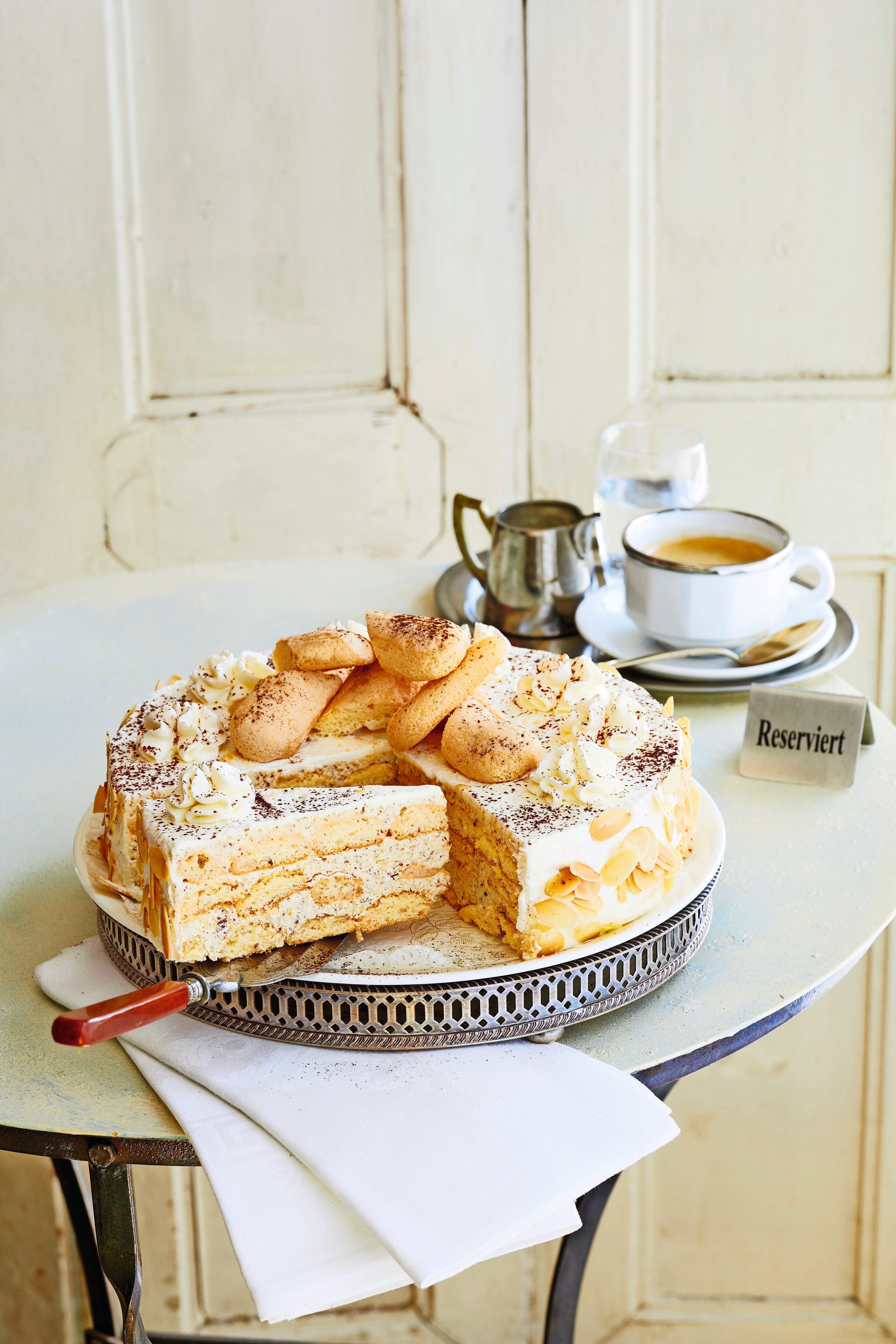 Österreichische Malakoff-Torte mit Mandeln, Löffelbiskuits und Kaffee auf einem gedeckten Tisch.
