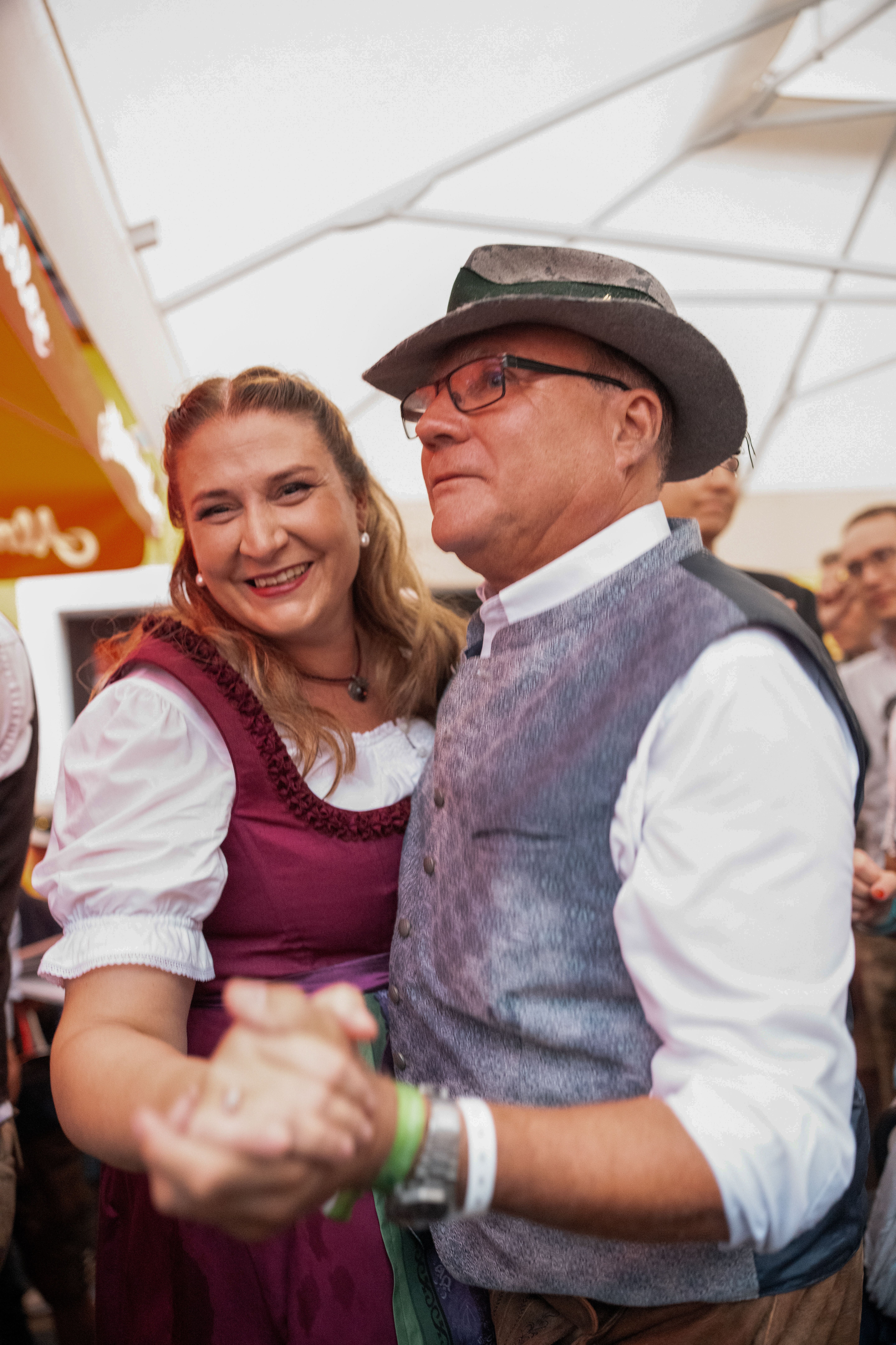 Ein Paar in Tracht tanzt und lächelt auf einem Volksfest oder Kirtag.