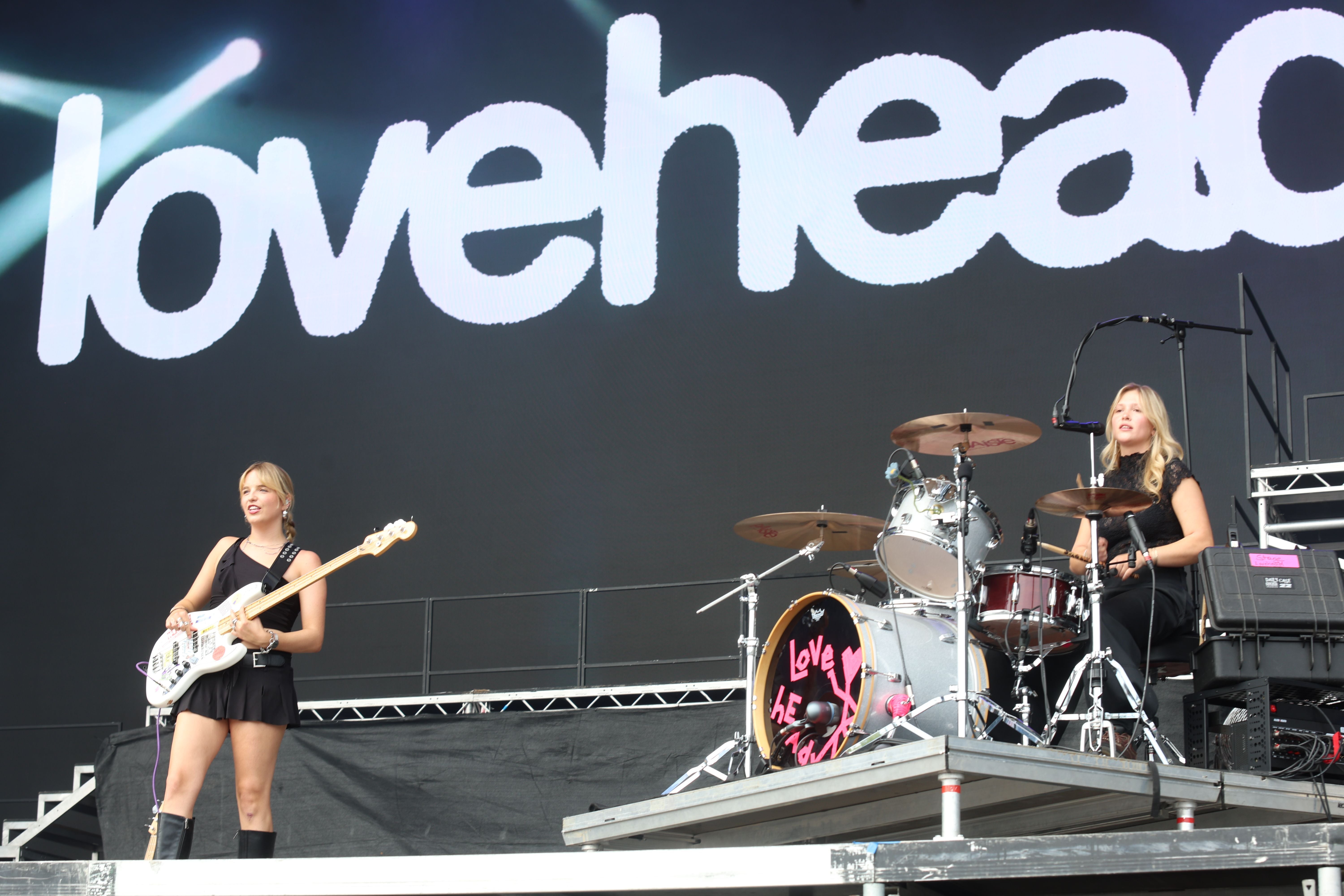Zwei Musikerinnen von Lovehead Frequency spielen Bass und Schlagzeug auf einer Festivalbühne.