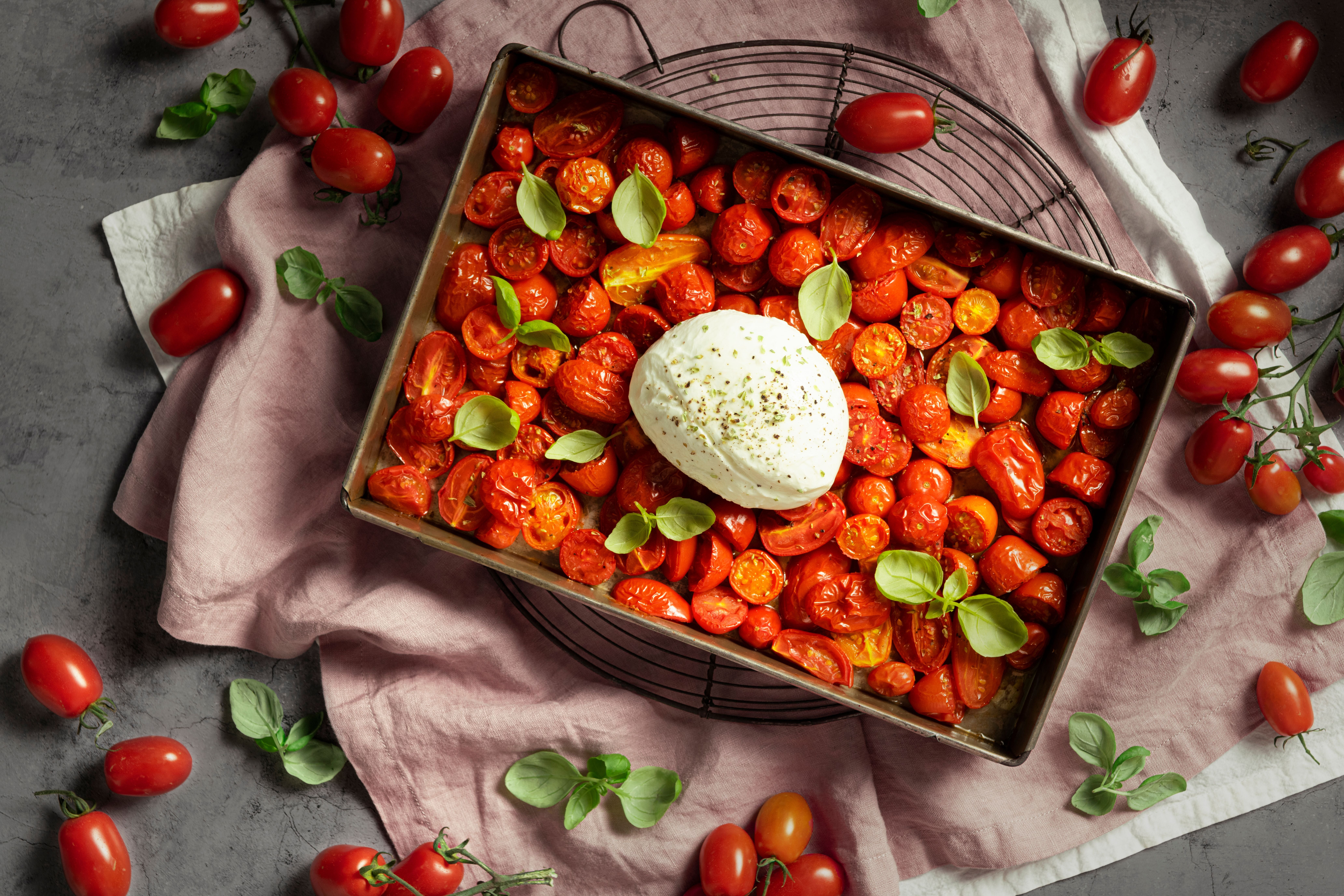 Im Ofen gebackene Tomaten mit Mozzarella und frischem Basilikum in einer Backform.