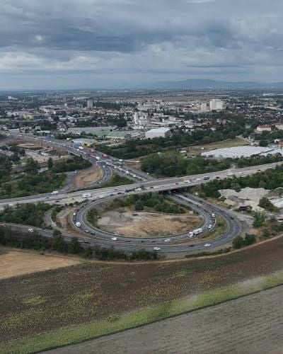 Luftbild des Verkehrsknoten Schwechat mit Autobahnen und Kreisverkehren unter bewölktem Himmel.
