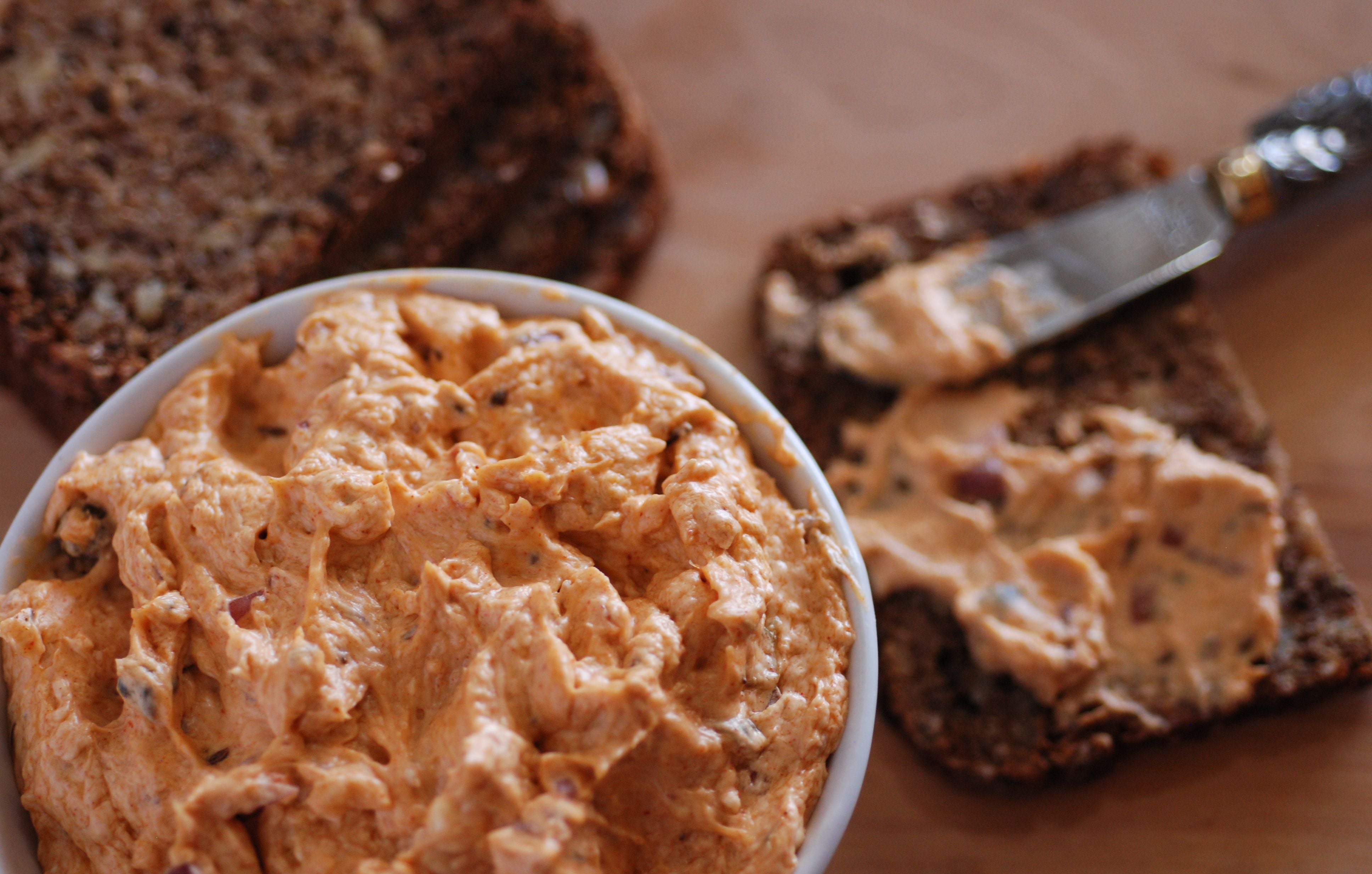 Liptauer Käseaufstrich auf dunklem Brot, daneben eine Schale mit dem Aufstrich.
