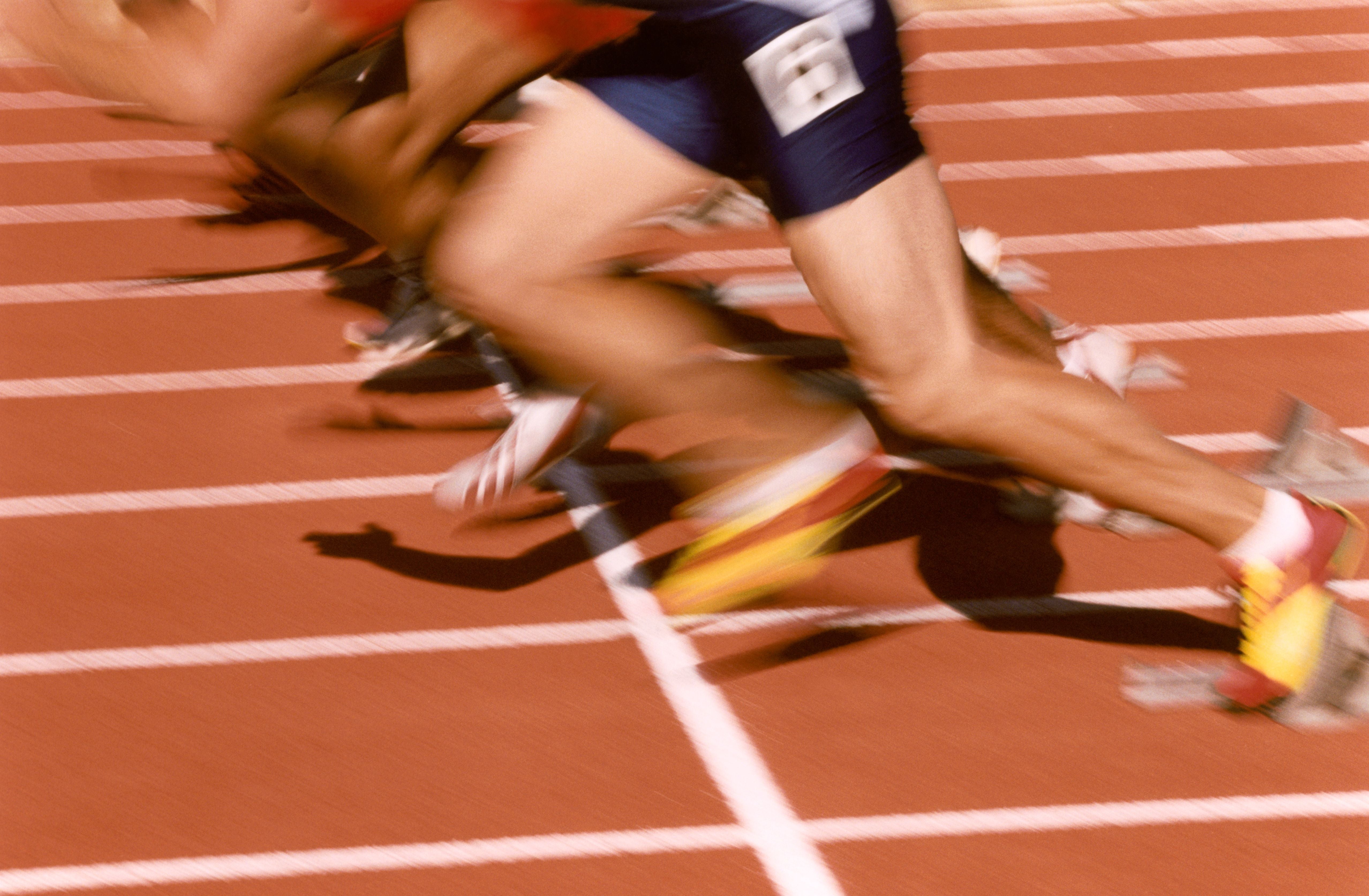 Mehrere Sprinter starten gleichzeitig von ihren Startblöcken auf einer Laufbahn.