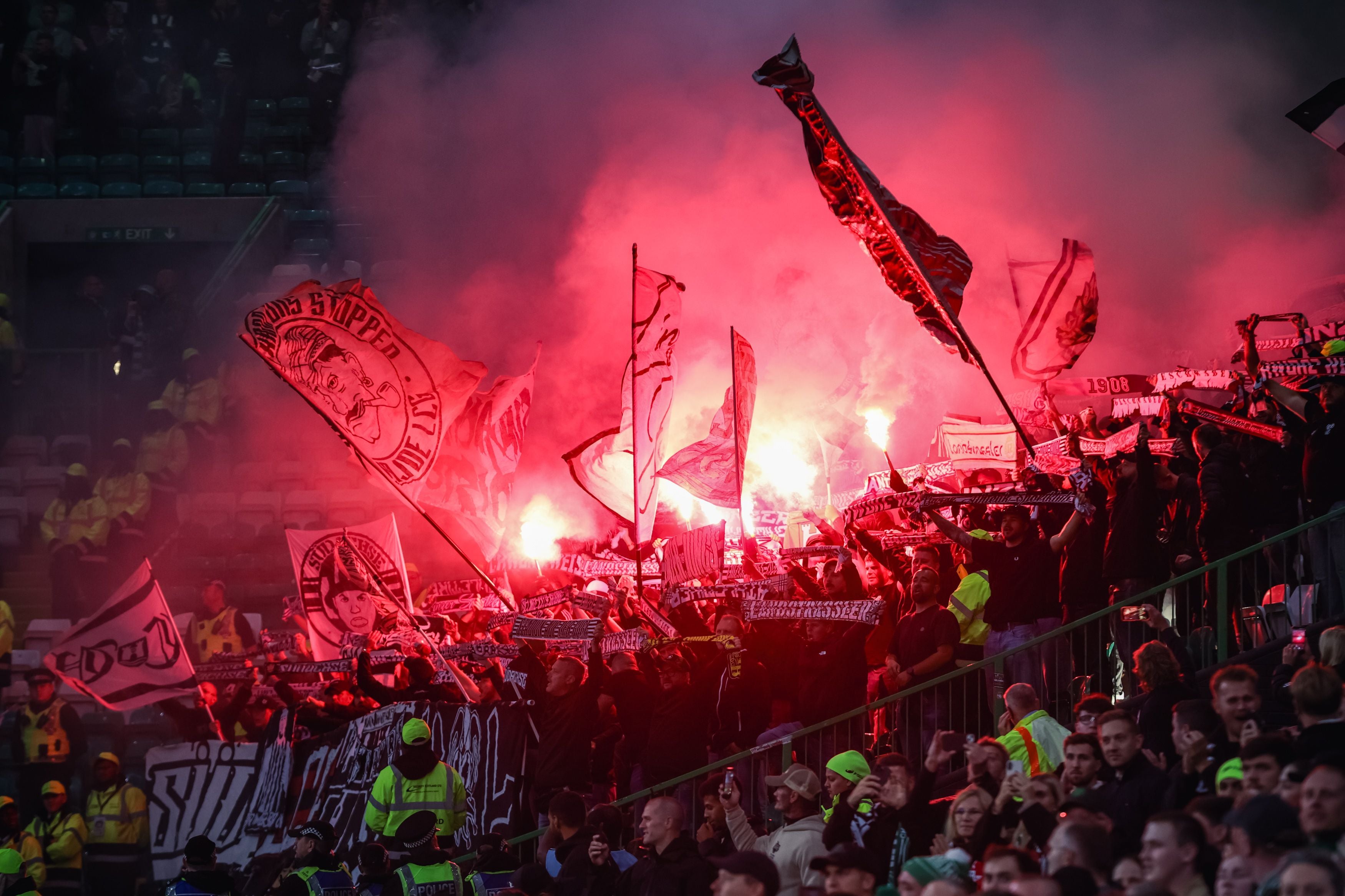 Fans des LASK zünden Bengalos und schwenken Fahnen im Stadion während eines Fußballspiels.