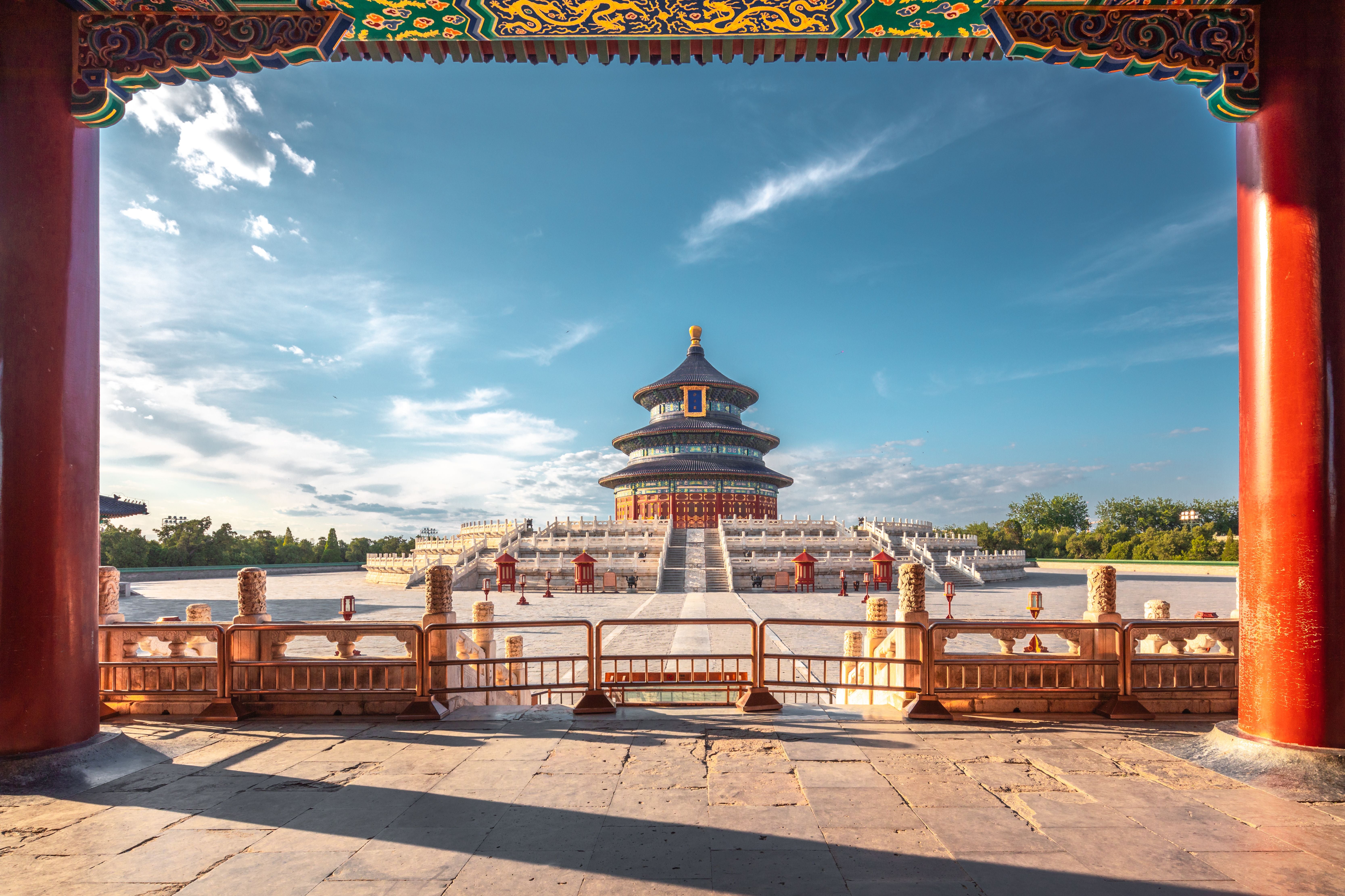Der Himmelstempel in Peking mit rundem Hauptgebäude, umgeben von steinernen Balustraden und blauem Himmel.