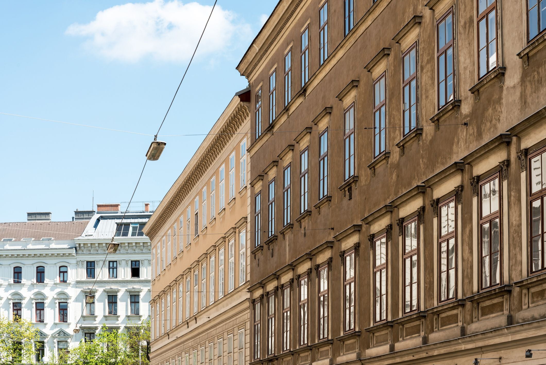 Fassaden von Wohnhäusern im Wiener Klassizismusstil bei blauem Himmel.