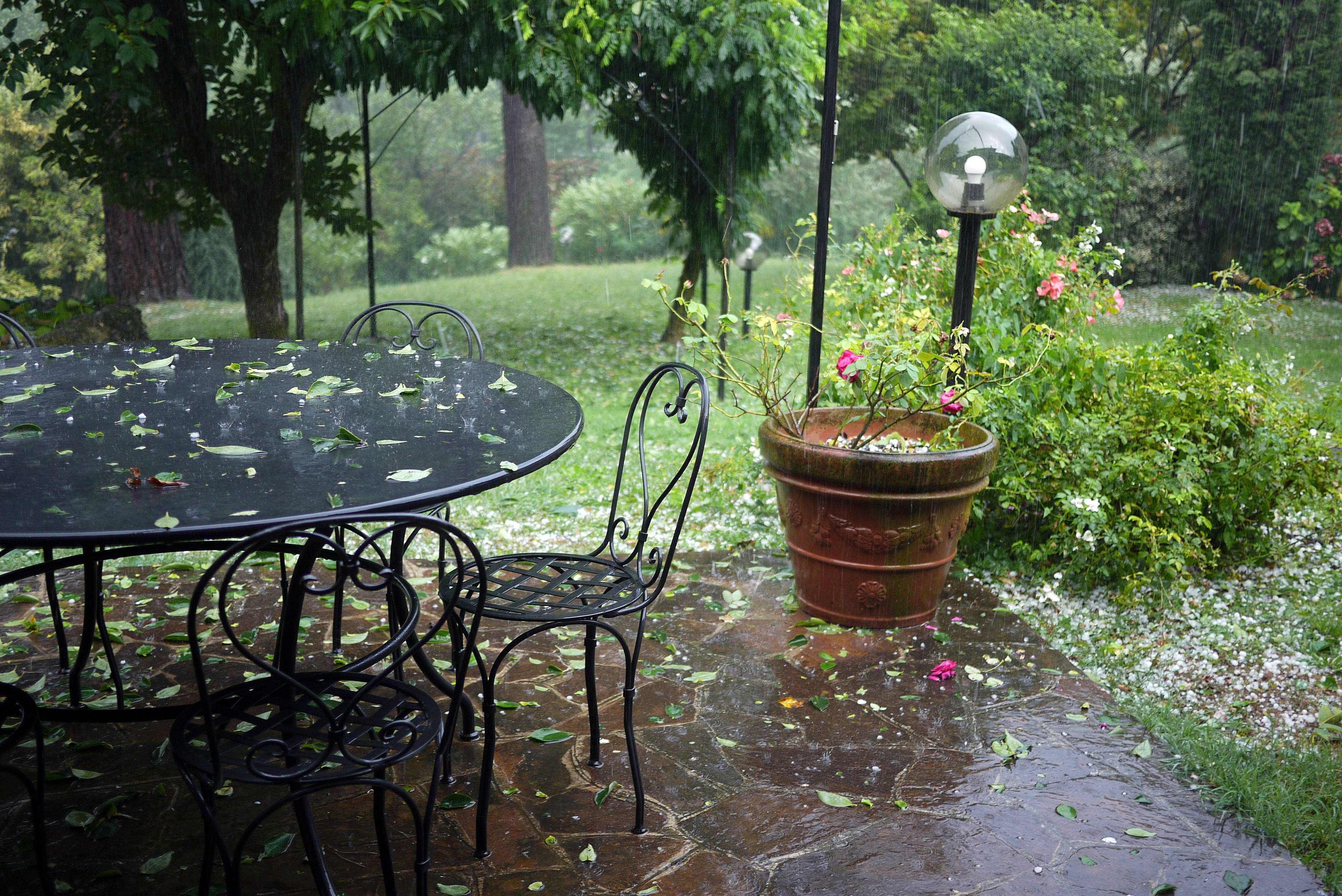 Garten mit Eisenteich und Stühlen, Blumentopf, Lampe, viele Blätter und Hagel auf dem Boden.