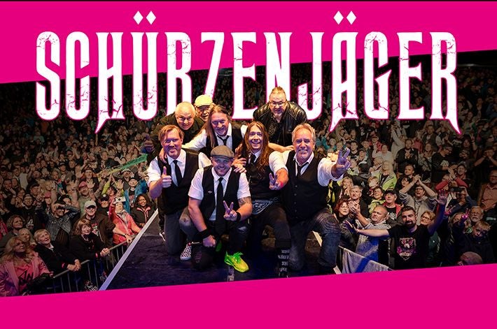 Band Schürzenjäger posiert auf der Bühne vor einem großen jubelnden Publikum.