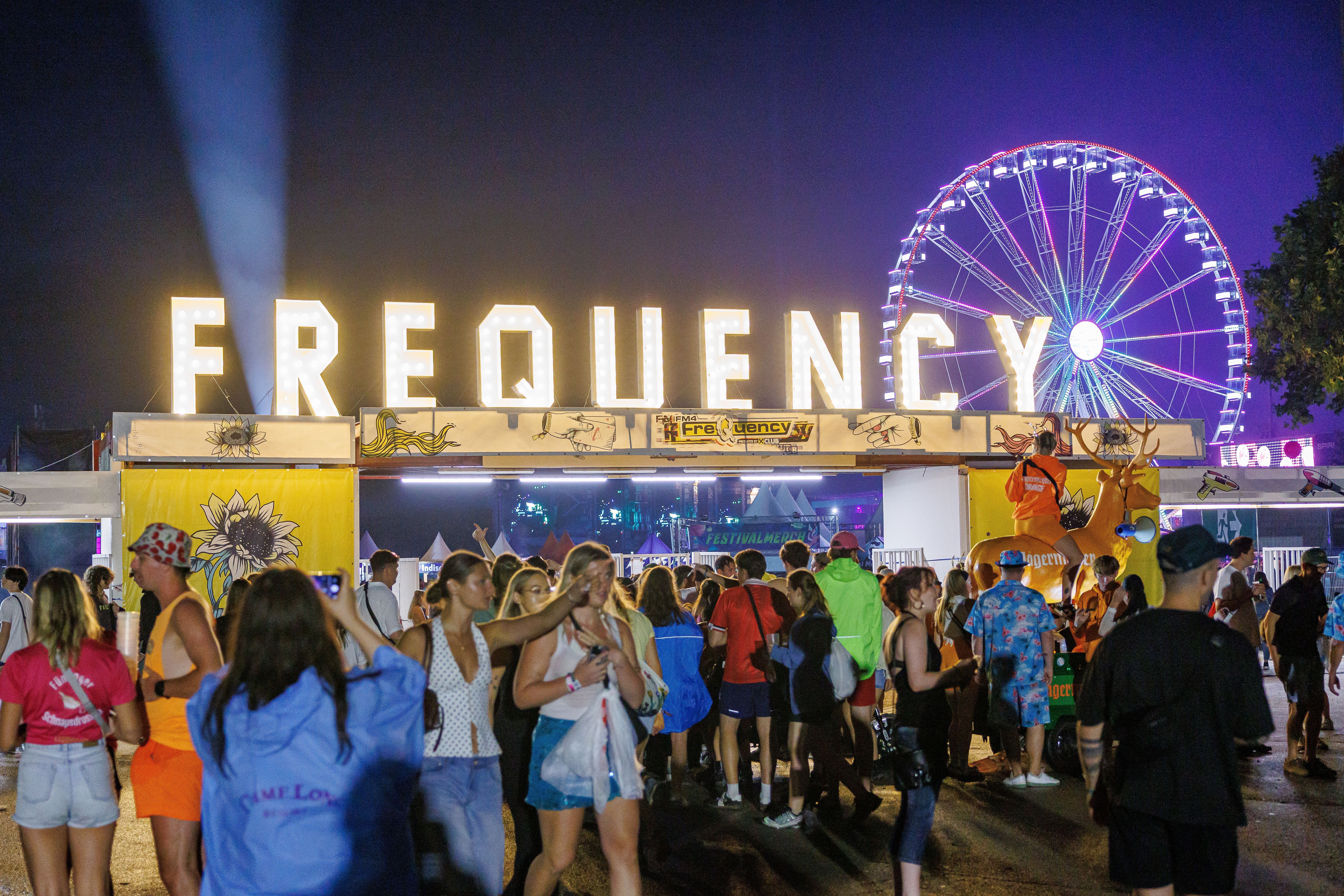 Festivalbesucher beim Frequency Festival 2026 in St. Pölten mit beleuchtetem Riesenrad im Hintergrund.