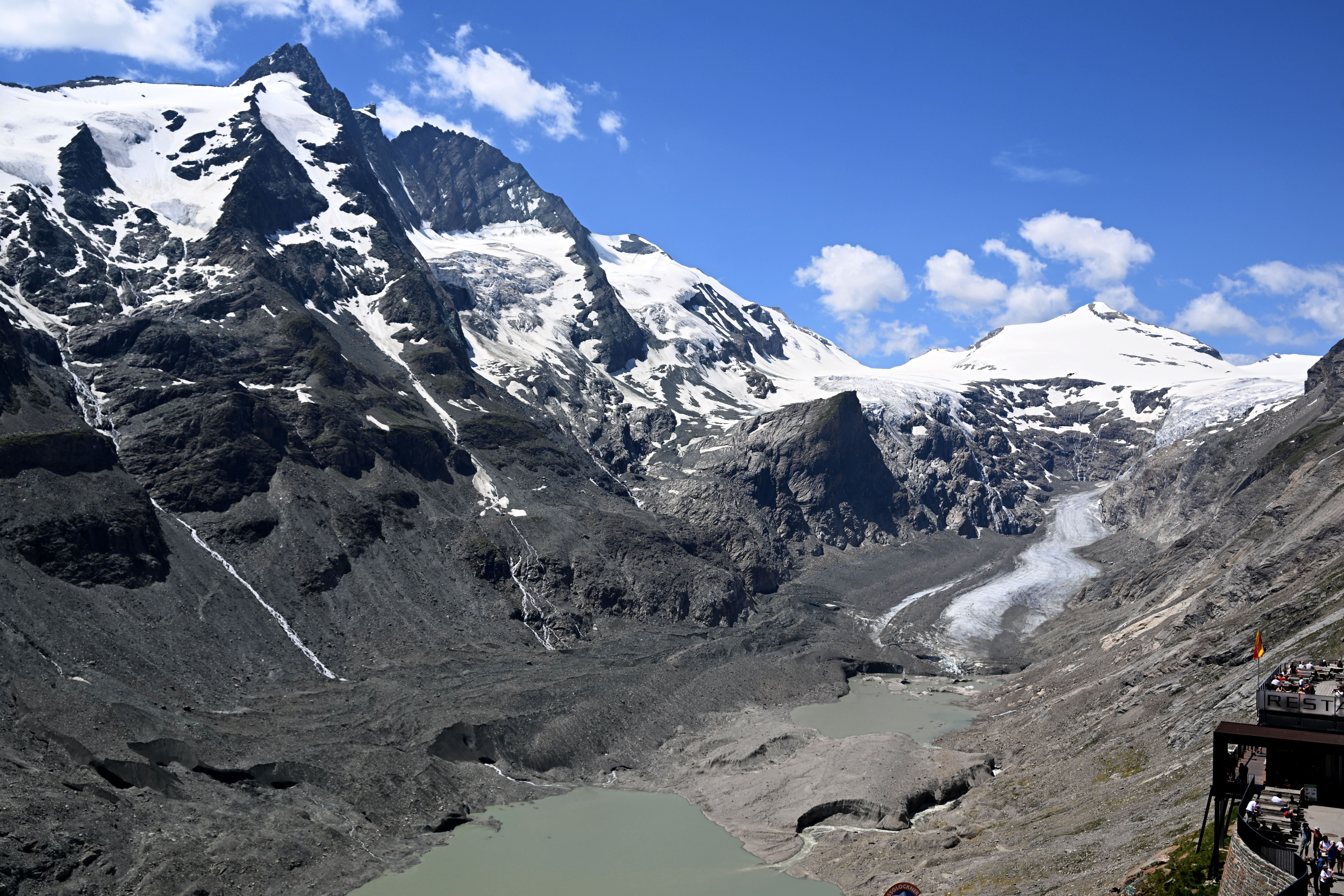 Blick auf die schmutzig-graue Pasterze, Gletschersee und Großglockner bei klarem Himmel.