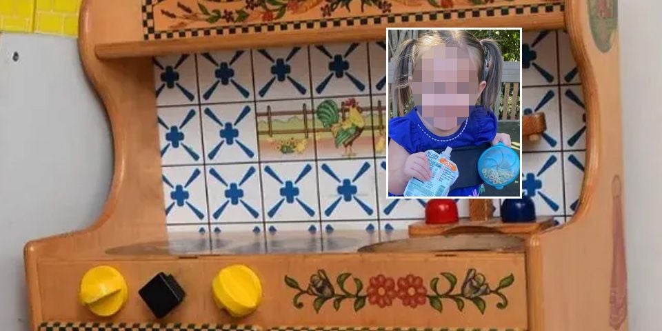 Kinderspielküche aus Holz mit gelben Knöpfen und Foto eines verpixelten Mädchens darüber.