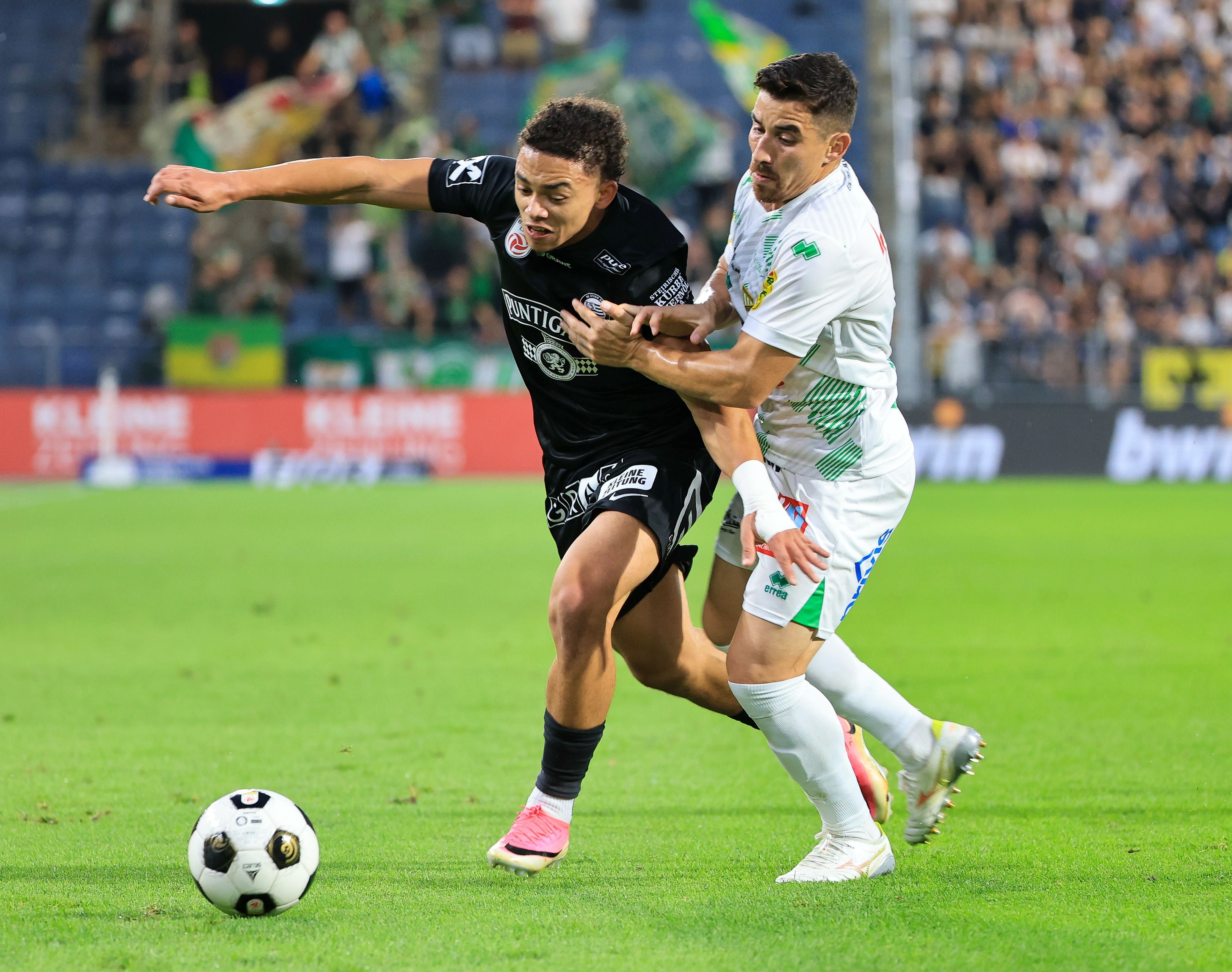 Zwei Fußballspieler kämpfen während eines Spiels um den Ball auf dem Spielfeld.
