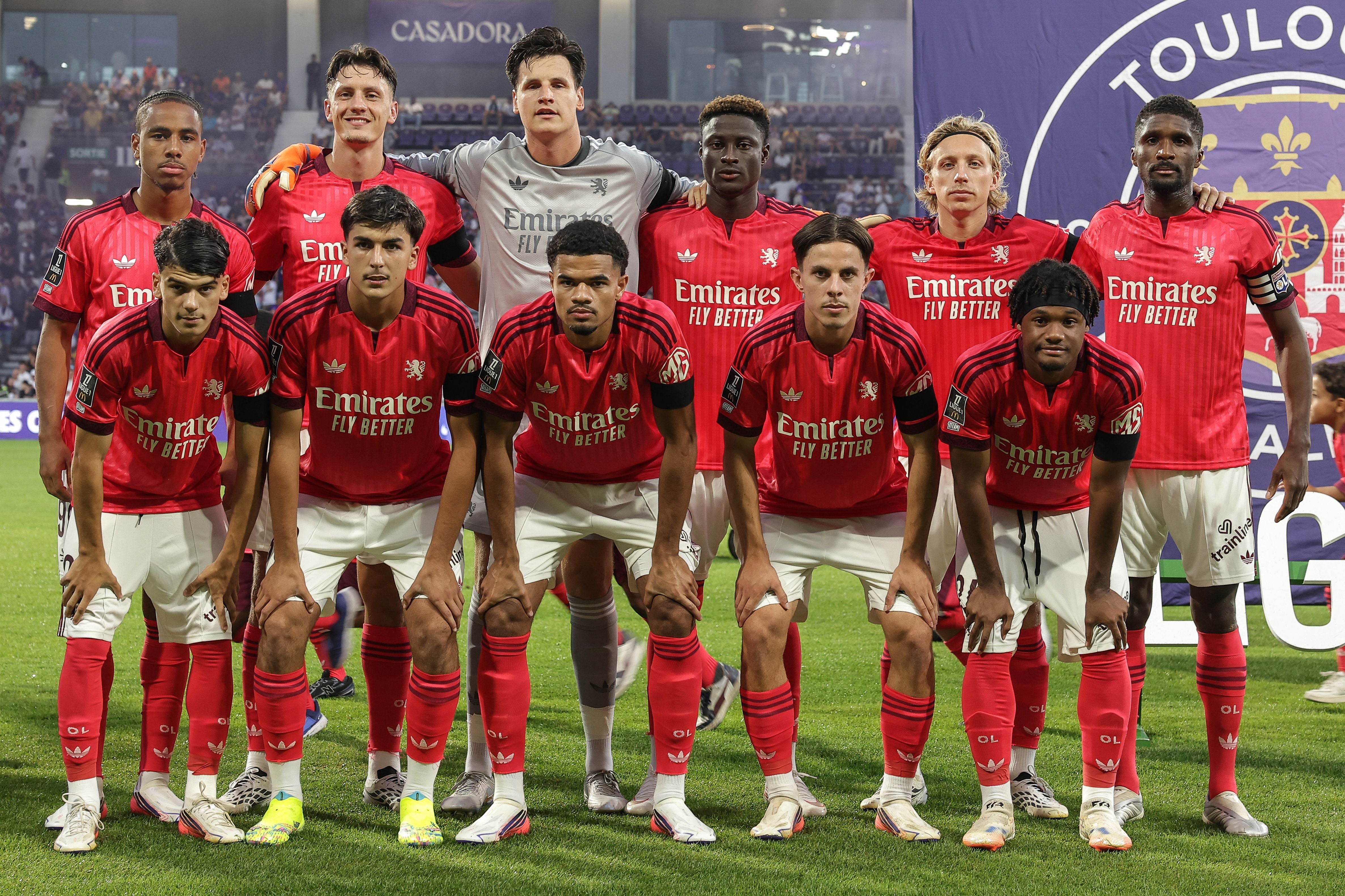 Elf Spieler von Olympique Lyon posieren vor einem Fußballspiel in roten Trikots für ein Mannschaftsfoto.