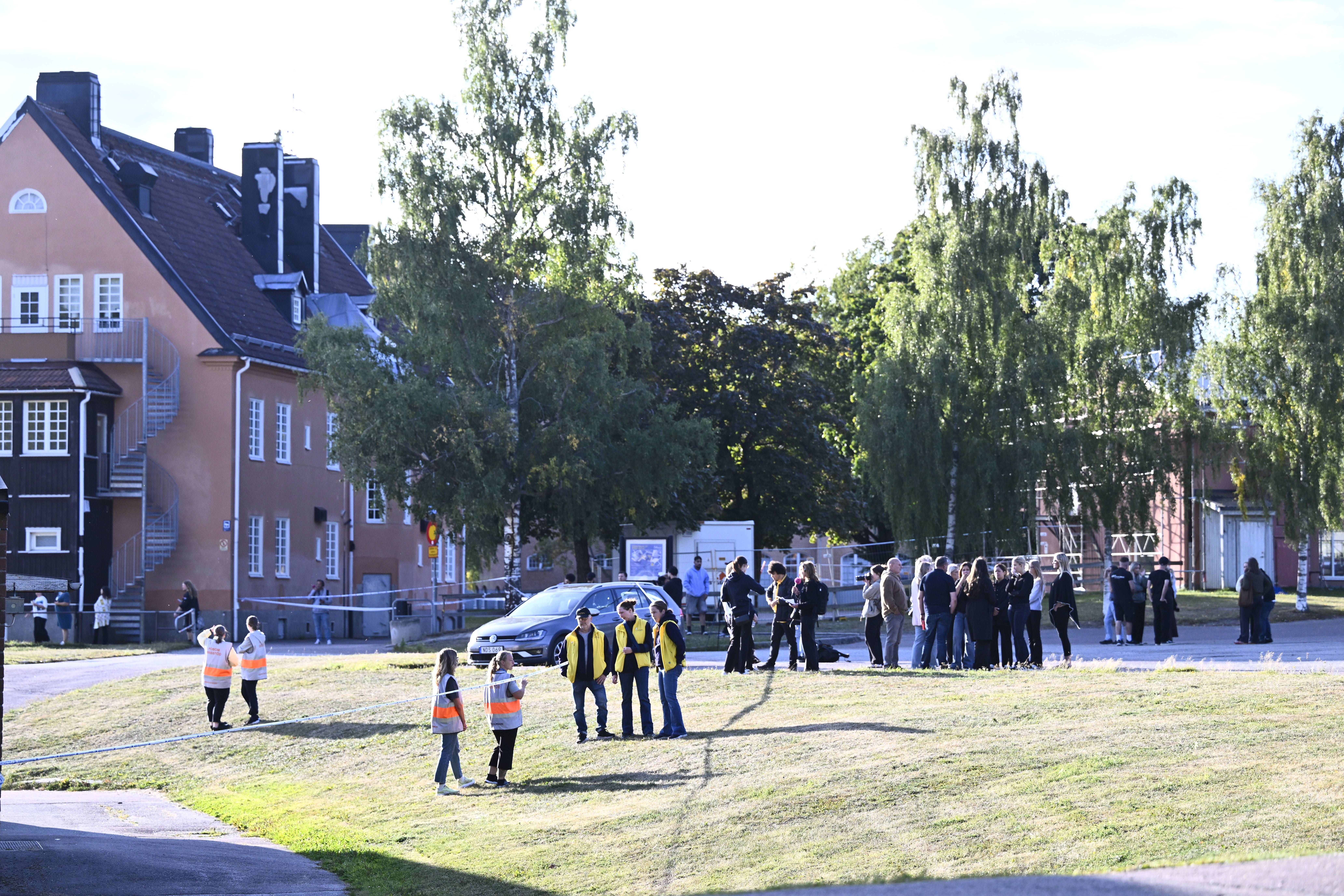 Polizei und Rettungskräfte vor einer Schule in Fagersta, Menschen stehen in Gruppen auf dem Gelände.