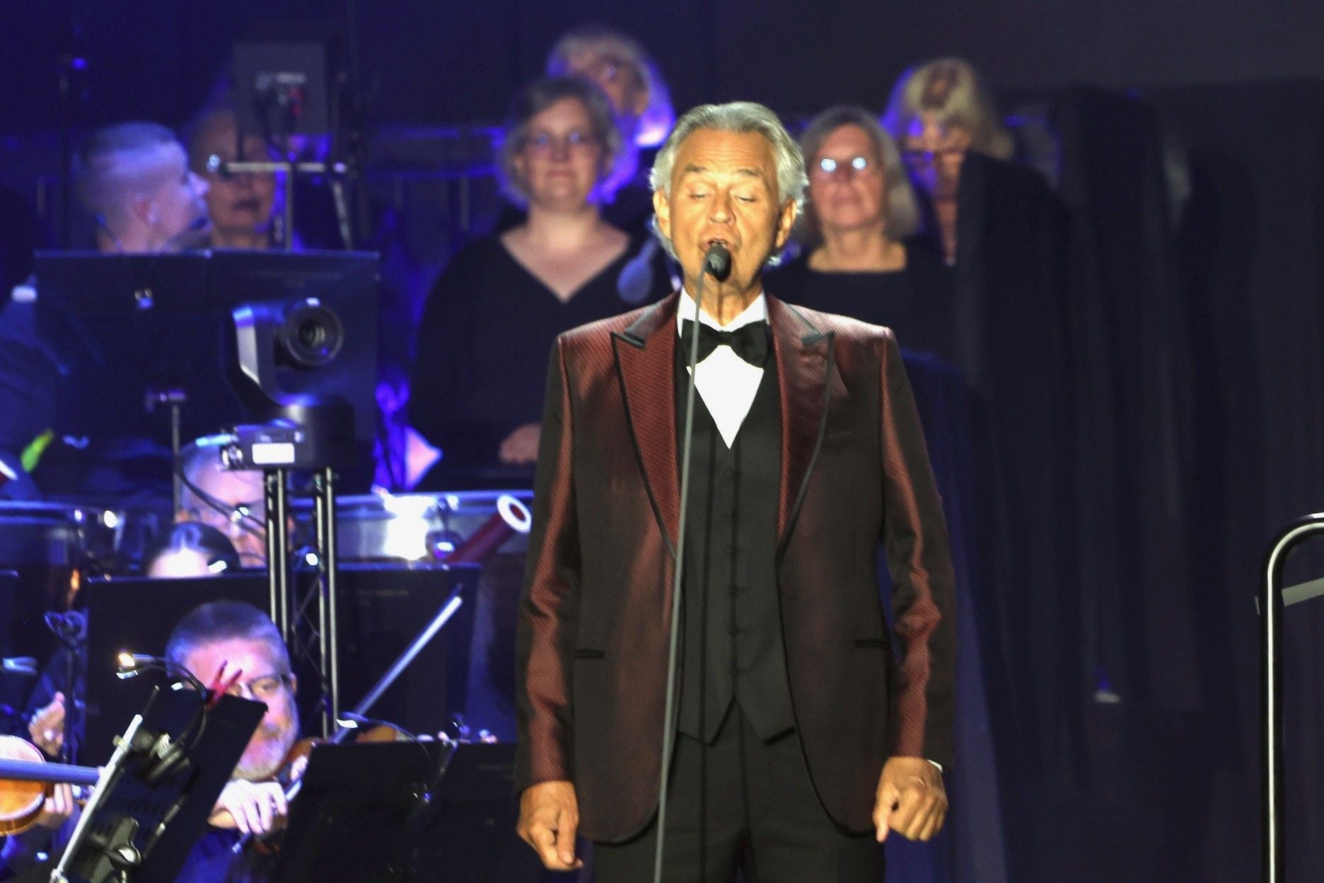 Andrea Bocelli singt auf der Bühne vor einem Orchester und Chor.