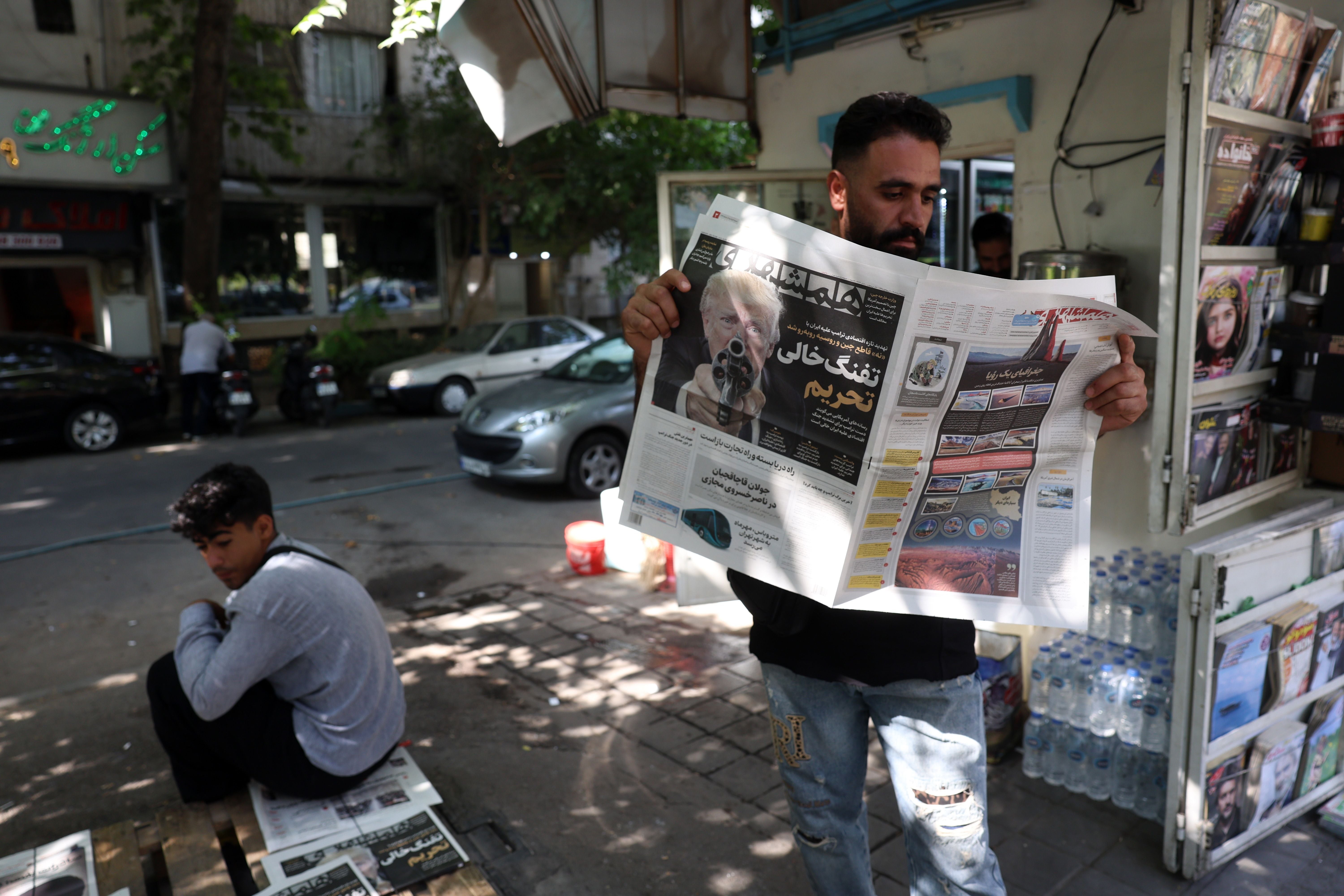 Ein Mann liest vor einem Kiosk in Teheran eine Zeitung mit Trump auf dem Titelblatt.