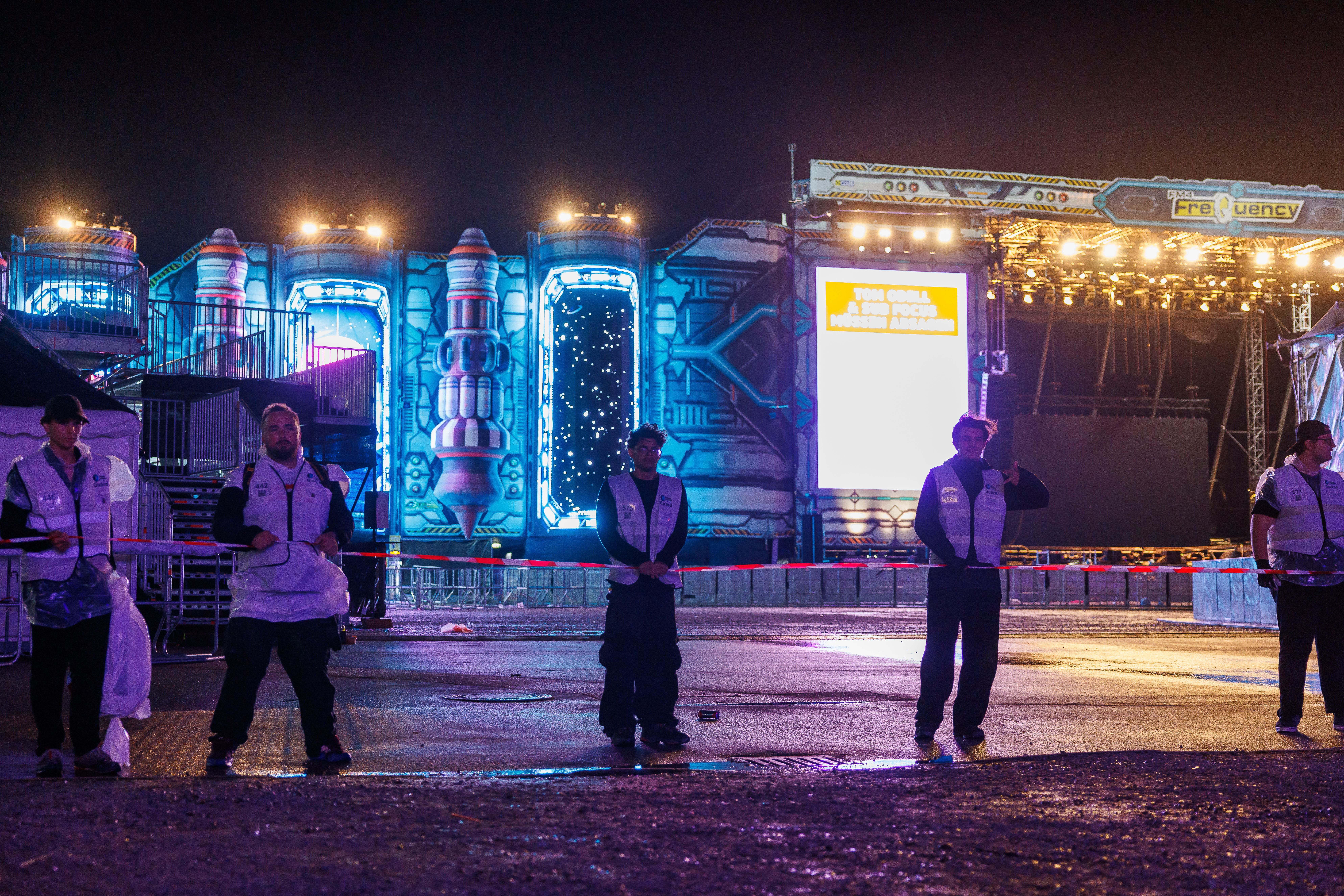 Securitymitarbeiter räumen nachts das Gelände vor der beleuchteten Space Stage beim Frequency Festival.
