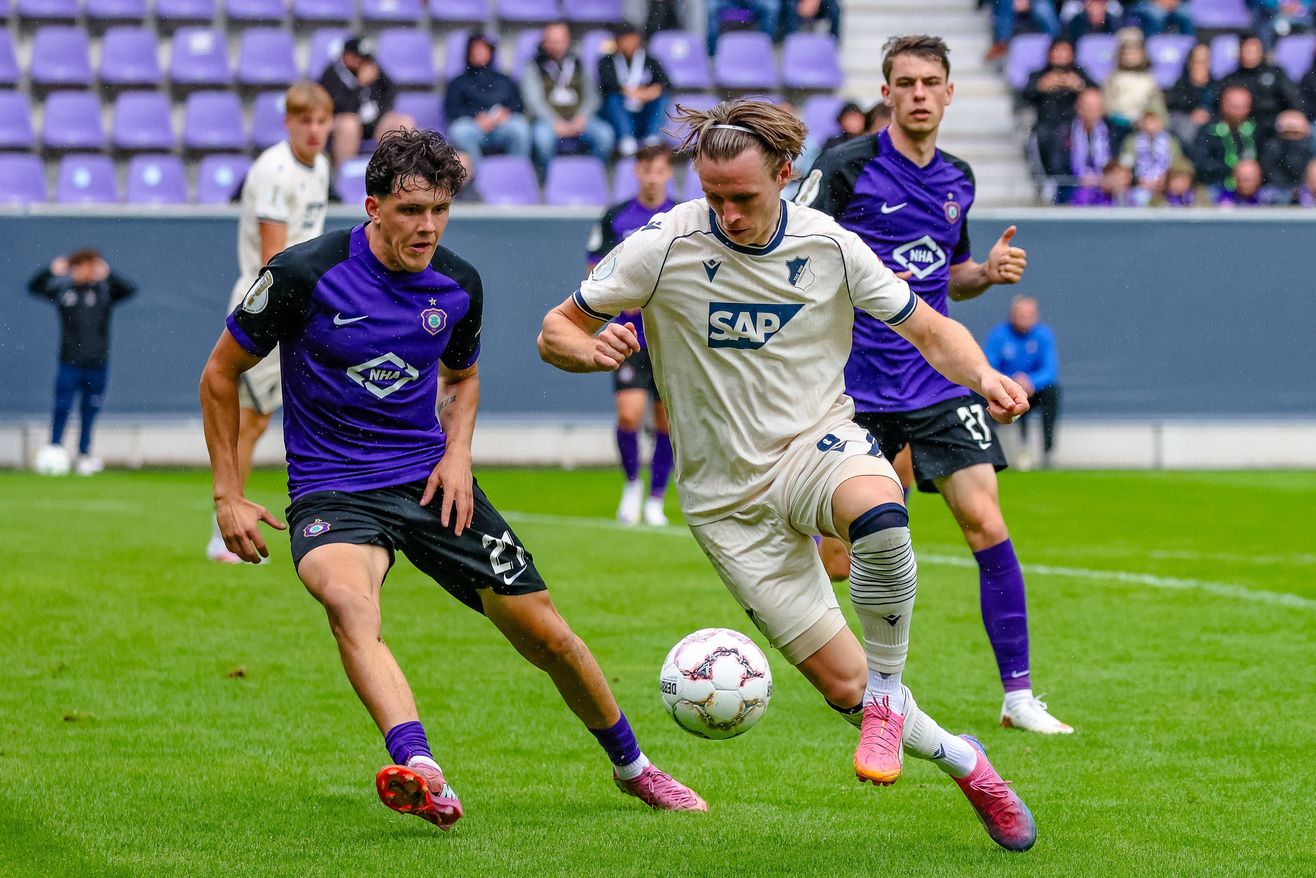 Zwei Fußballspieler im Zweikampf um den Ball während eines Spiels im Stadion.