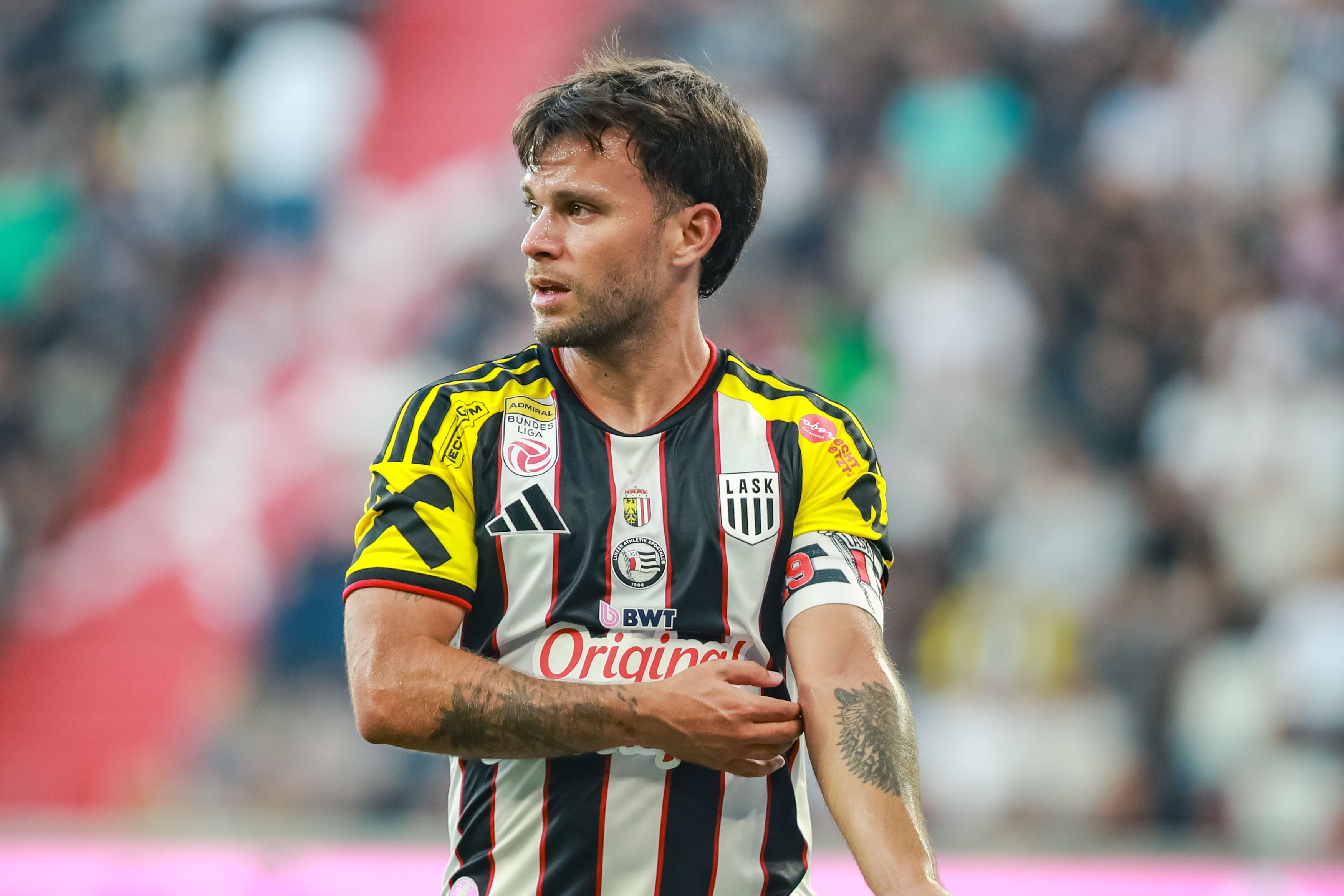 Ein Fußballspieler von LASK im gestreiften Trikot blickt nach links auf dem Spielfeld.