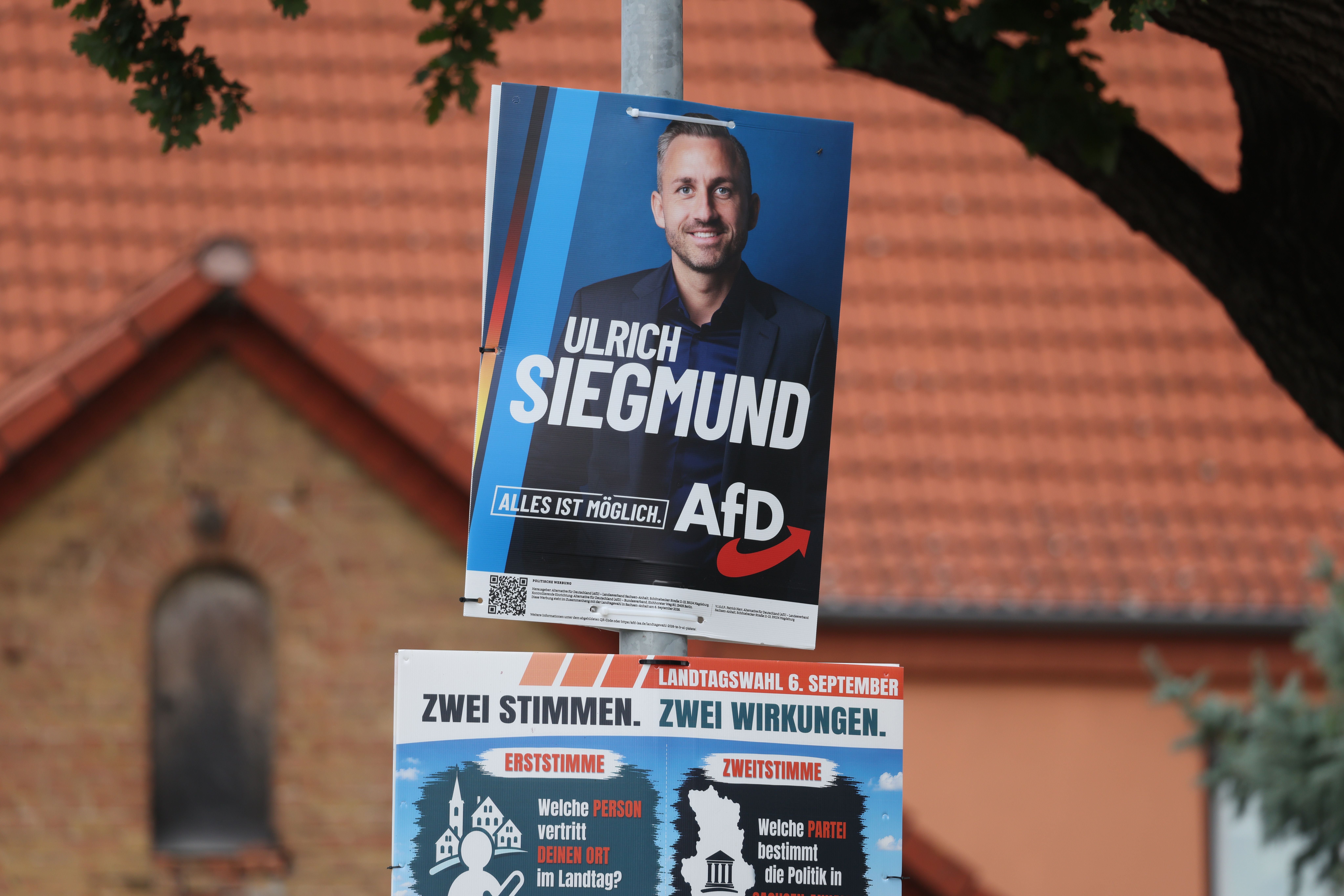 Ein Wahlplakat der AfD mit Ulrich Siegmund hängt an einem Laternenmast vor einem Gebäude.