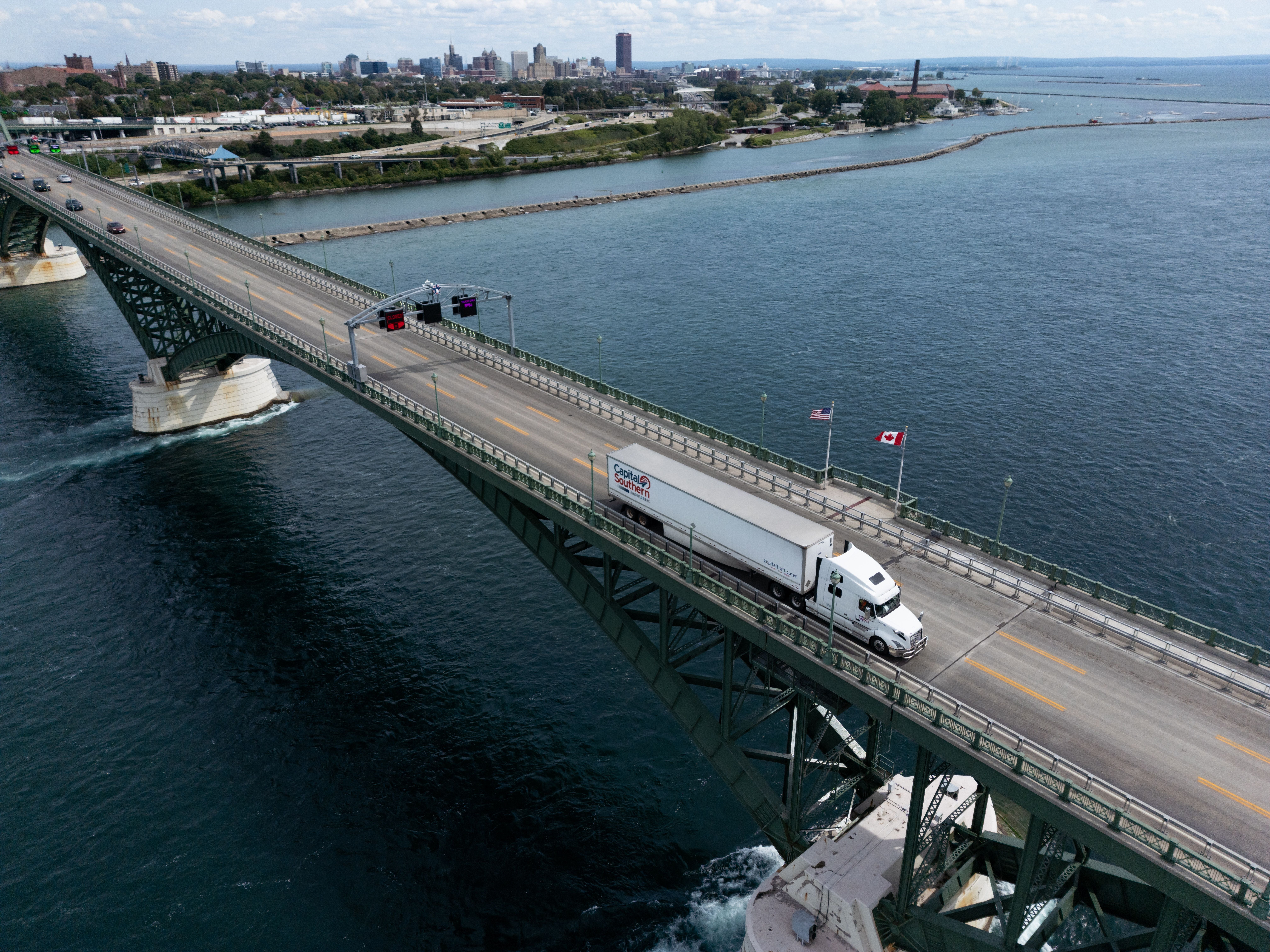 Ein Lastwagen überquert die Peace Bridge über den Fluss, mit US- und Kanada-Flaggen daneben.