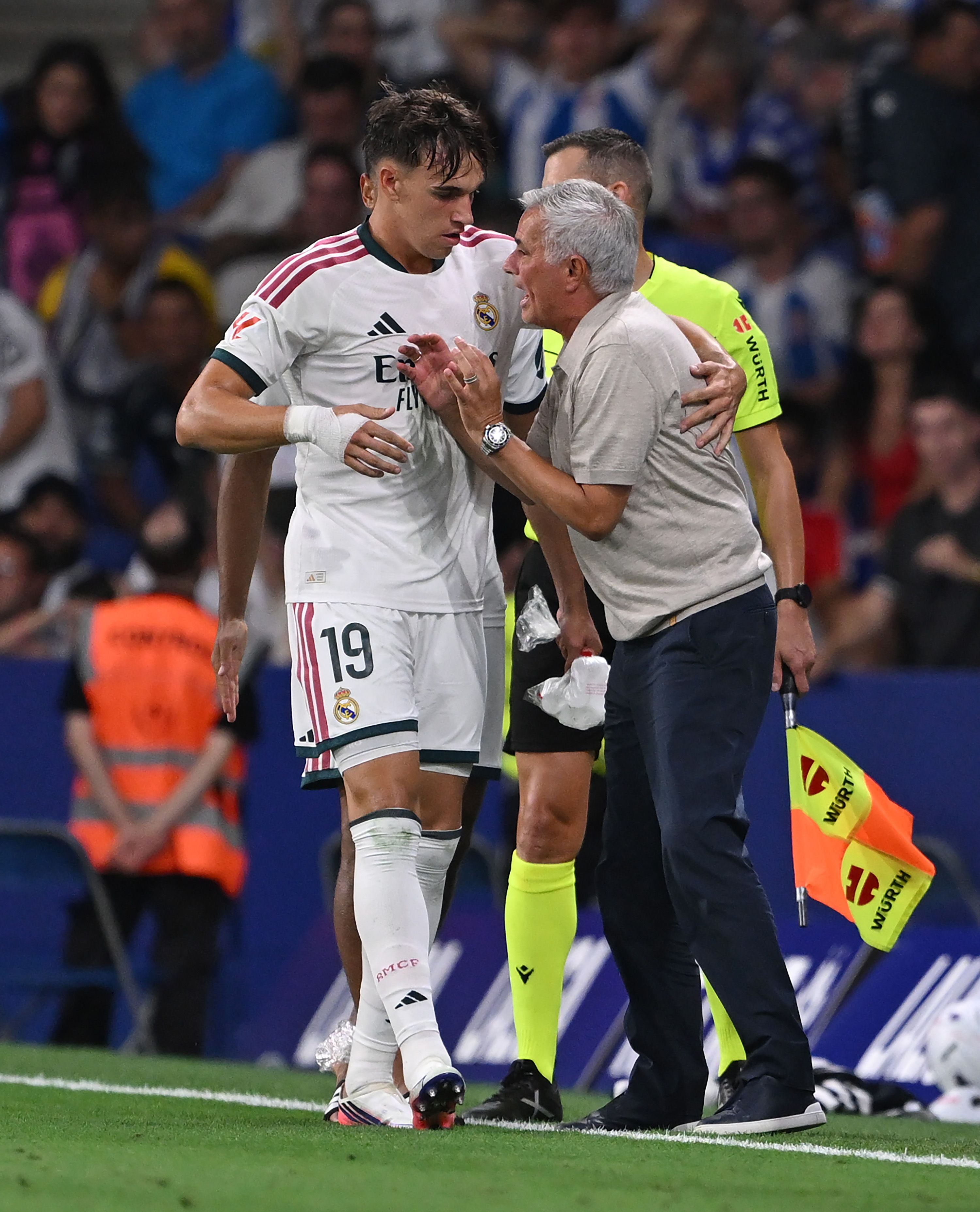 Ein Real-Madrid-Spieler feiert mit einem Trainer am Spielfeldrand, ein Schiedsrichter steht daneben.