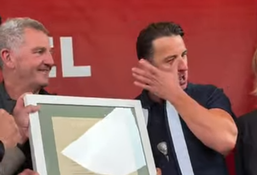 Andreas Gabalier wischt sich Tränen ab und hält eine gerahmte Urkunde.