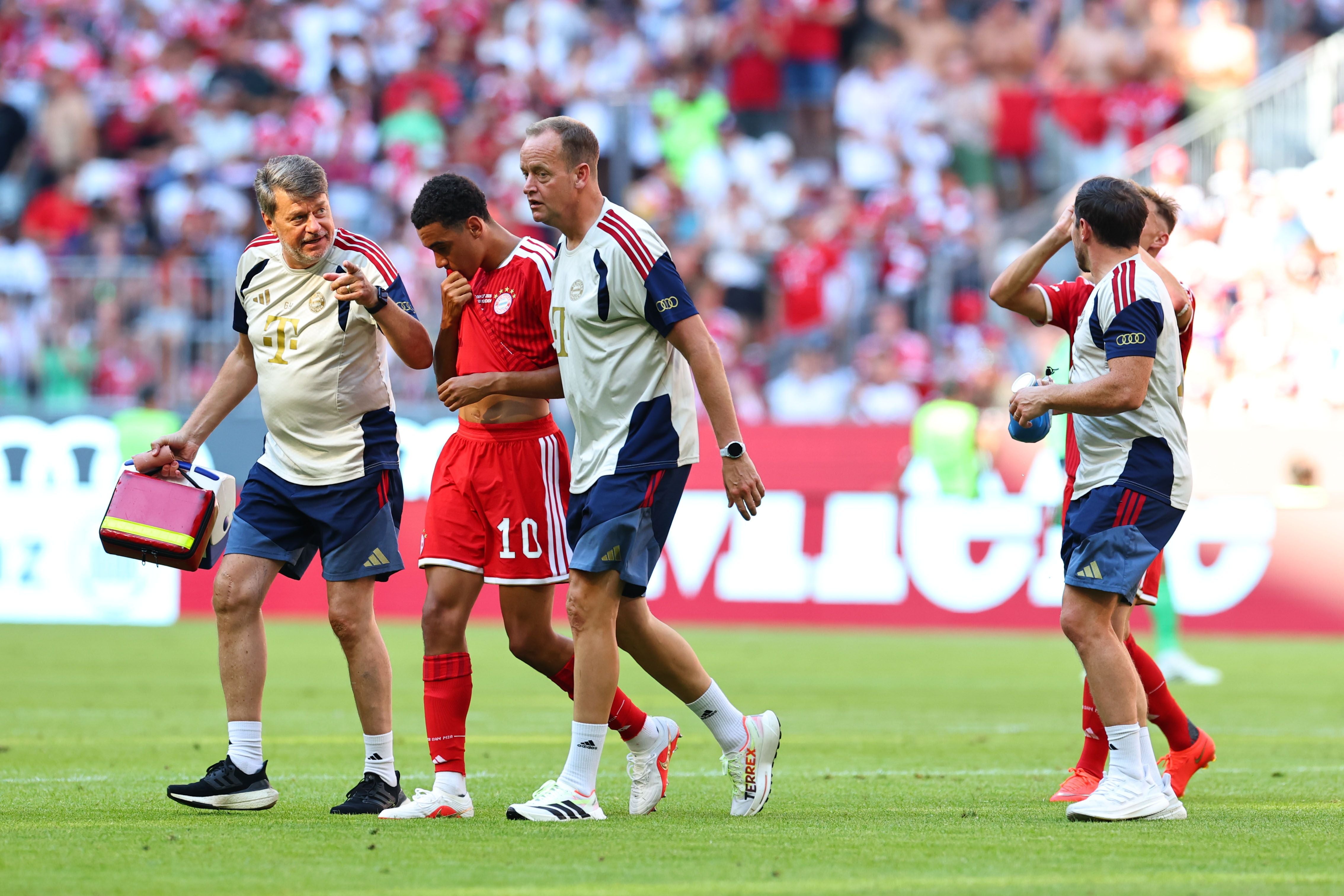 Jamal Musiala verlässt verletzt mit medizinischem Personal das Spielfeld beim Spiel Bayern gegen Leipzig.