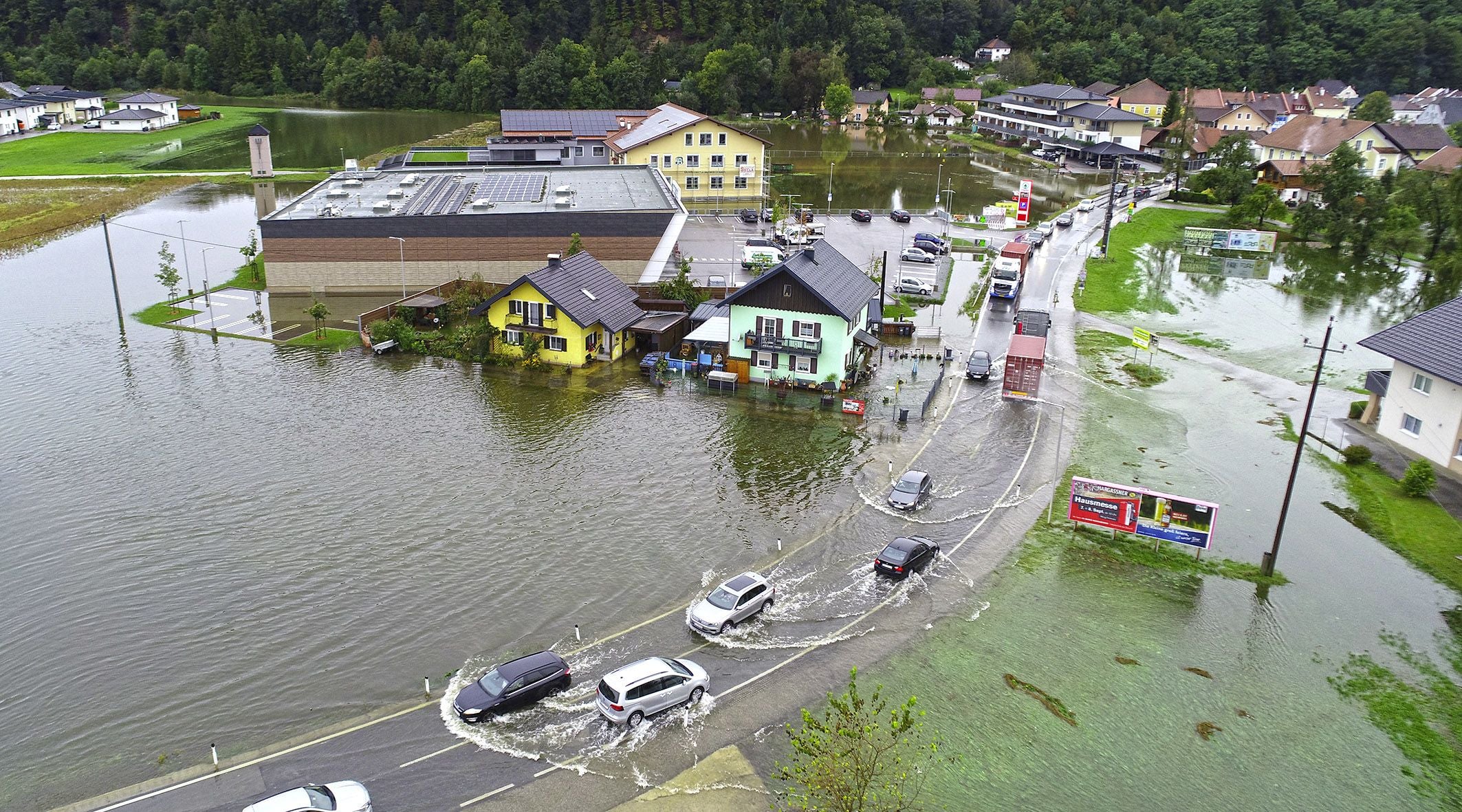 Überflutete Straßen und Häuser in Uttendorf, Autos fahren durch das Hochwasser, September 2024.