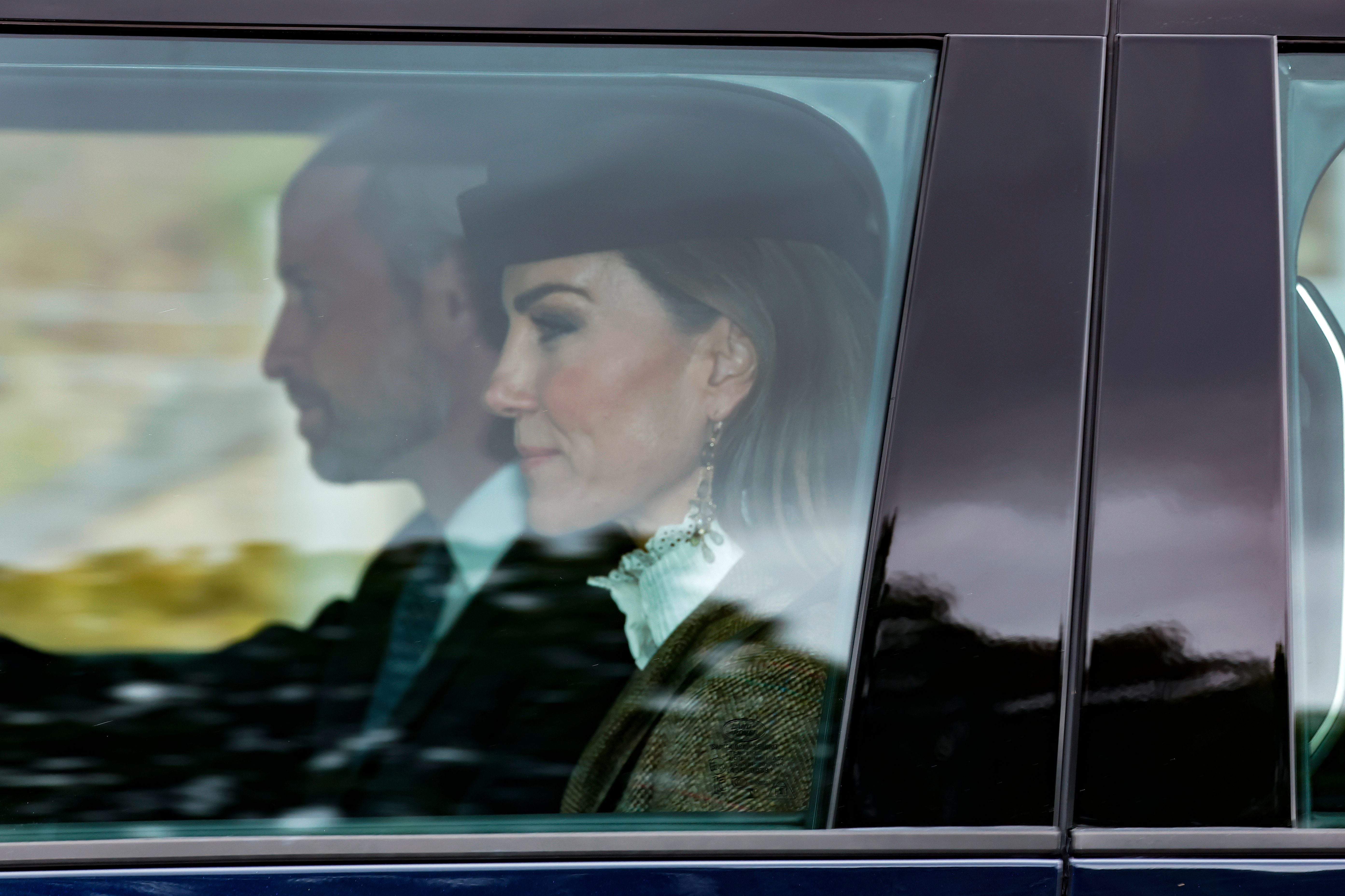 Ein Mann und eine Frau sitzen nebeneinander in einem Auto, fotografiert durch das Fenster.