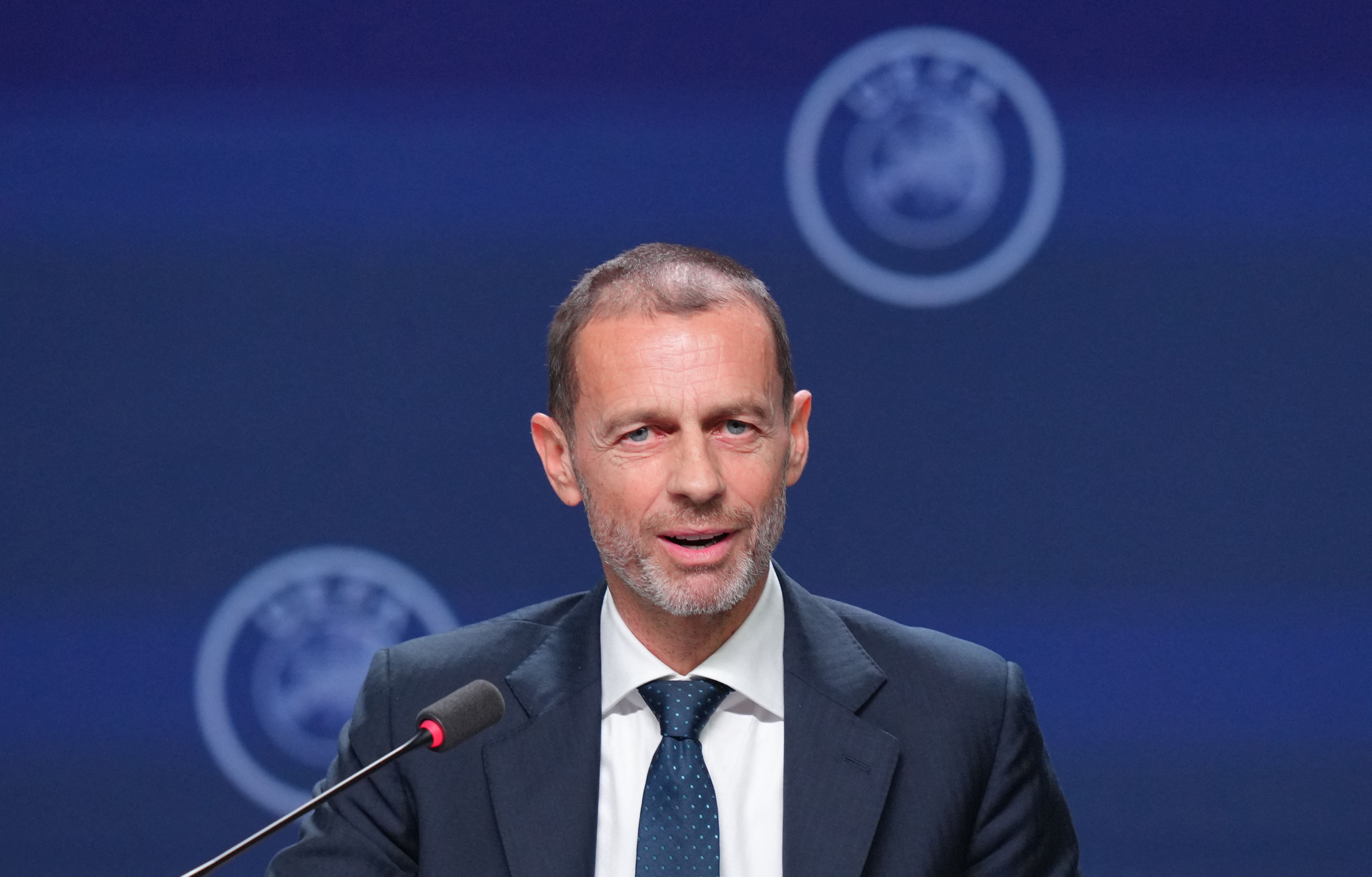 Ein Mann im Anzug spricht auf einer Pressekonferenz mit UEFA-Logo im Hintergrund.