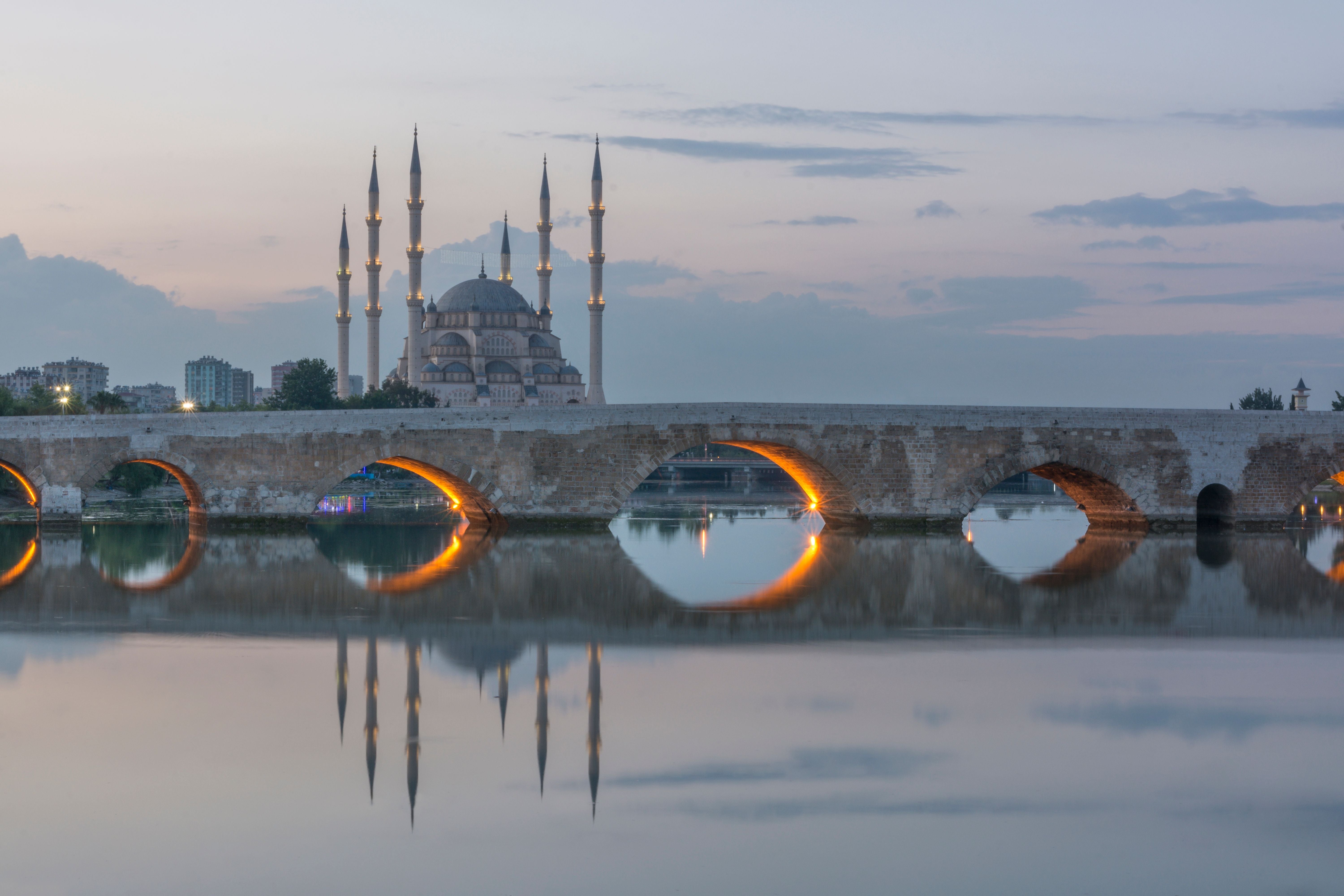 Sabanci-Moschee und Tasköprü-Brücke bei Abenddämmerung in Adana, gespiegelt im Fluss.