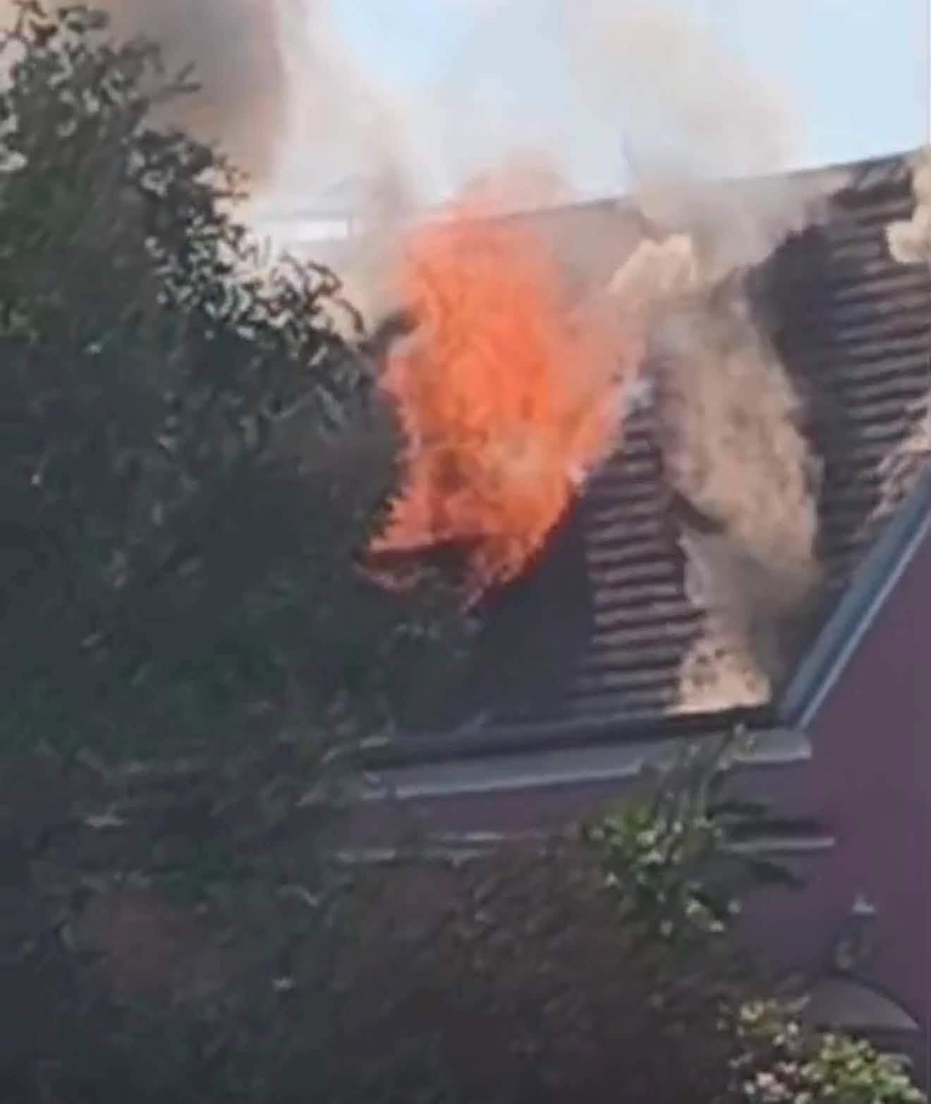 Flammen und Rauch steigen aus dem Dach eines Wohnhauses auf.