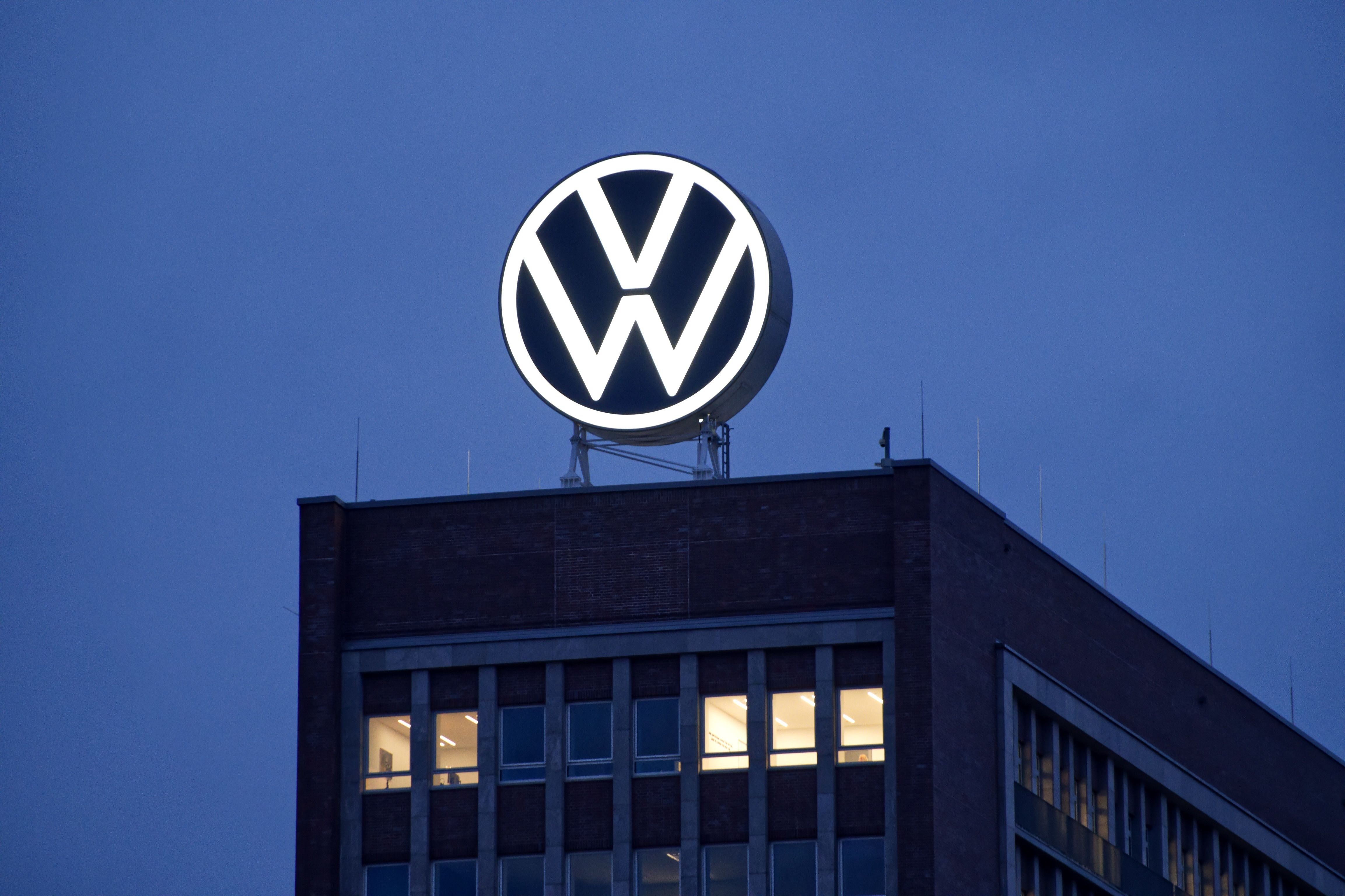 Leuchtendes VW-Logo auf dem Dach des Volkswagen-Hauptquartiers in Wolfsburg bei Abenddämmerung.