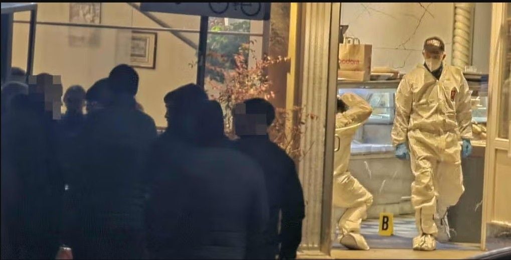 Kriminaltechniker in Schutzanzügen sichern Spuren in einem Lokal am Yppenplatz, Menschenmenge davor.
