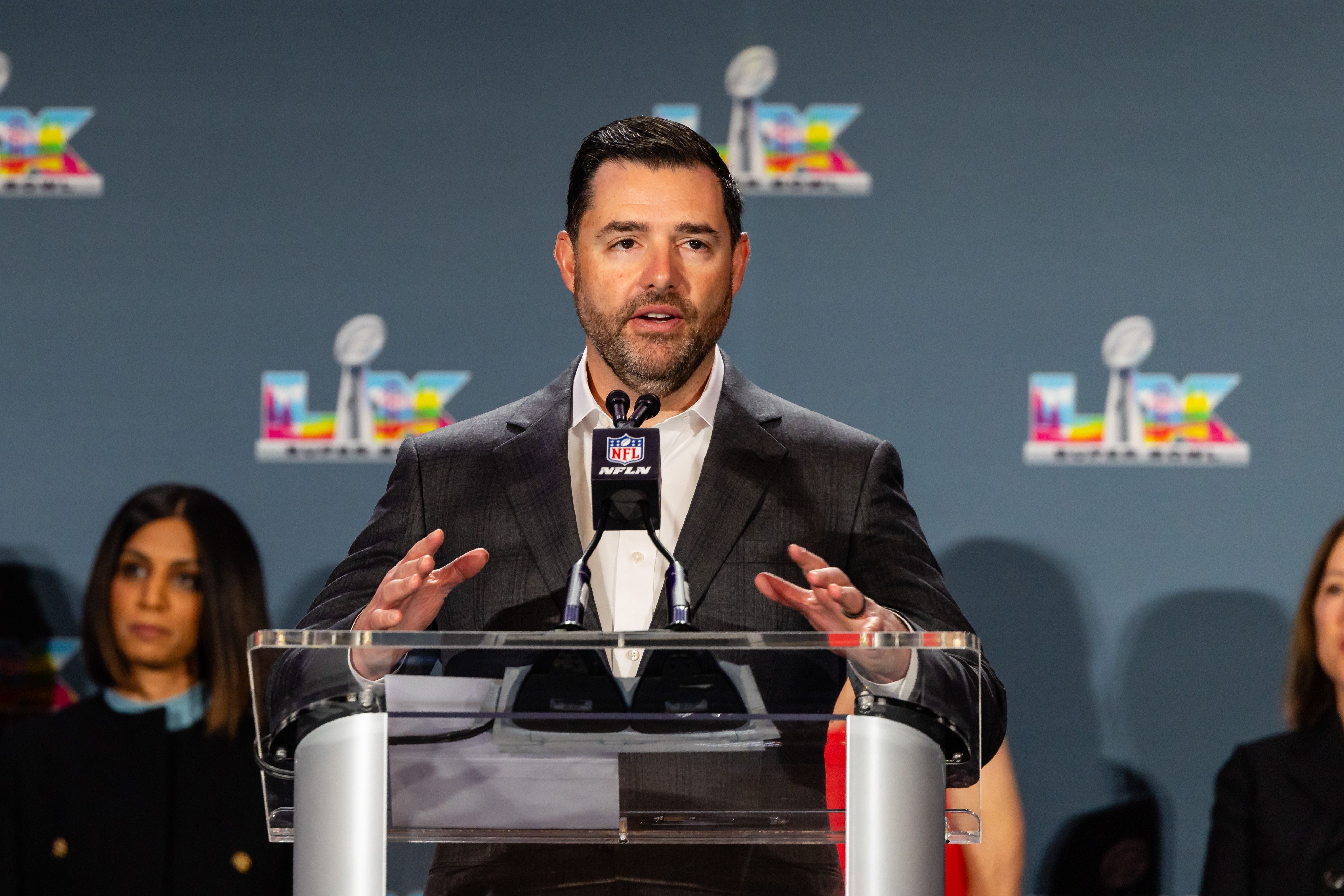 Ein Mann im Anzug spricht bei einer NFL-Pressekonferenz am Rednerpult mit Mikrofonen.