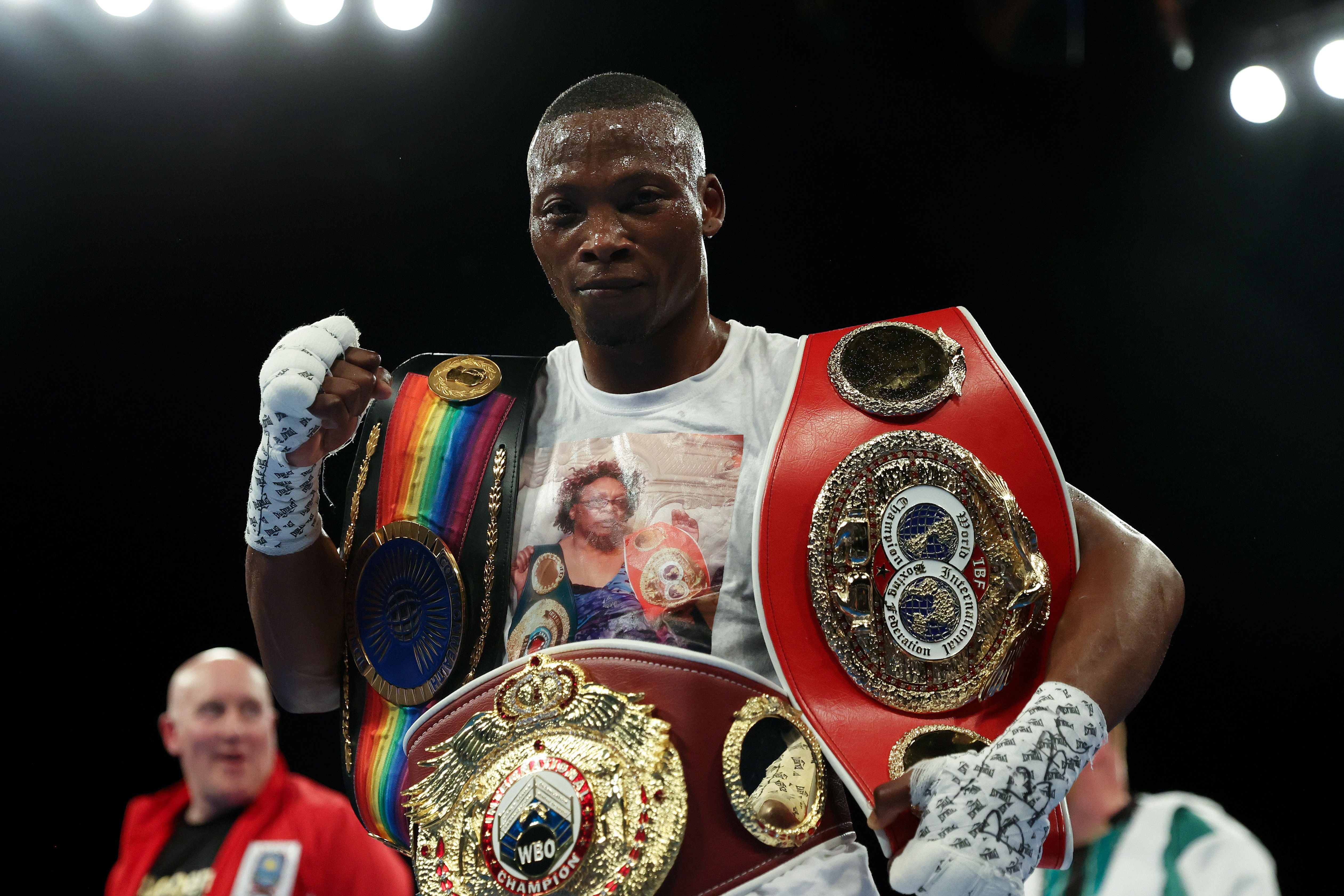 Ein Boxer feiert mit mehreren gewonnenen Meisterschaftsgürteln im Boxring.
