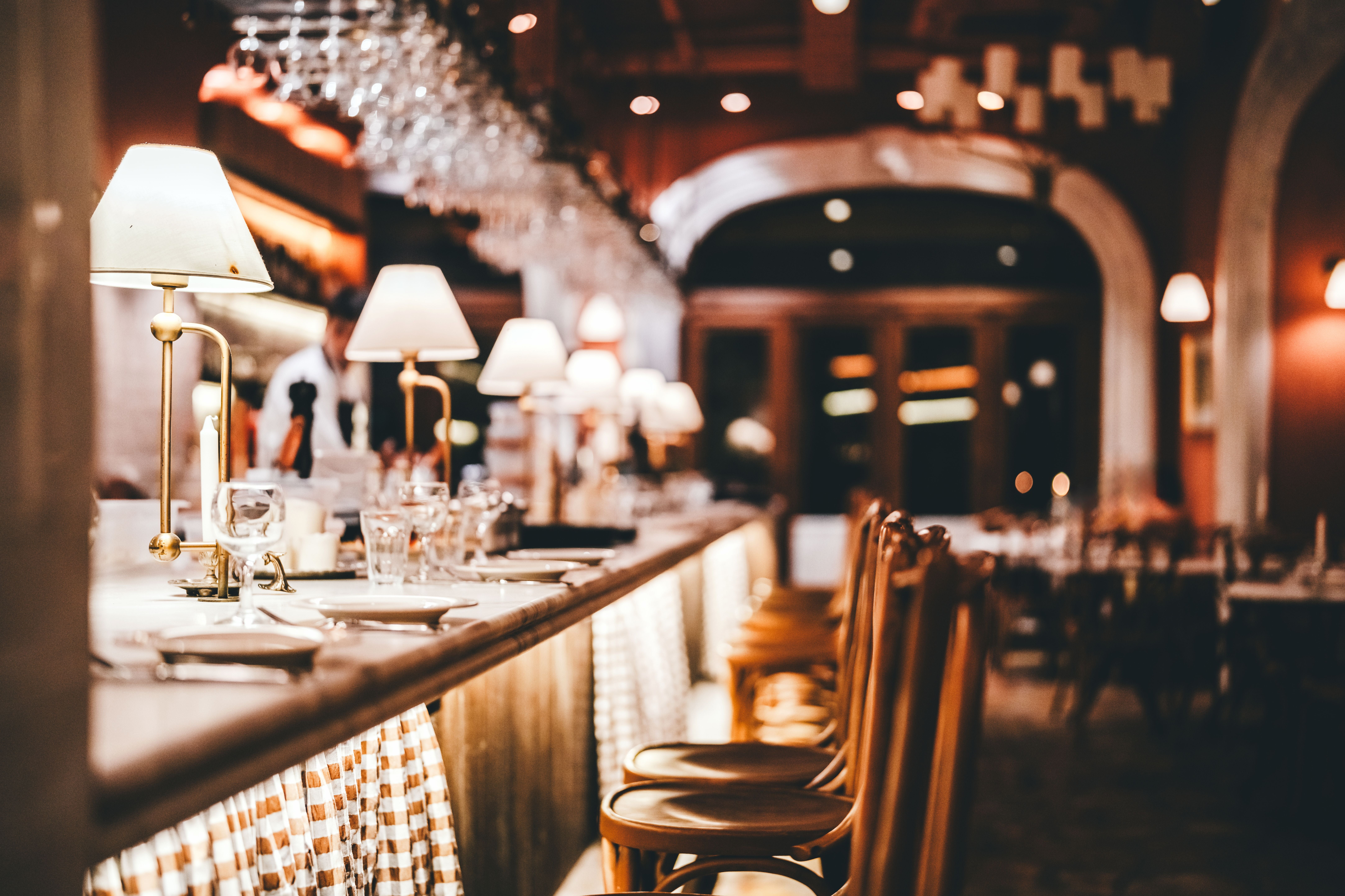 Stilvoller Restaurant-Barbereich mit sanfter Beleuchtung, Gläsern und Holzstühlen in gemütlicher Atmosphäre.