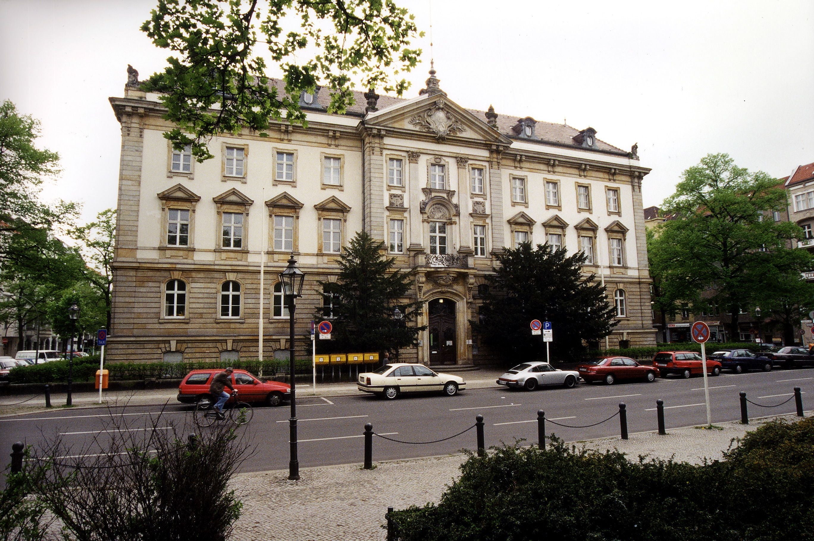 Das Amtsgericht Charlottenburg mit klassizistischer Fassade, davor geparkte Autos und Bäume.