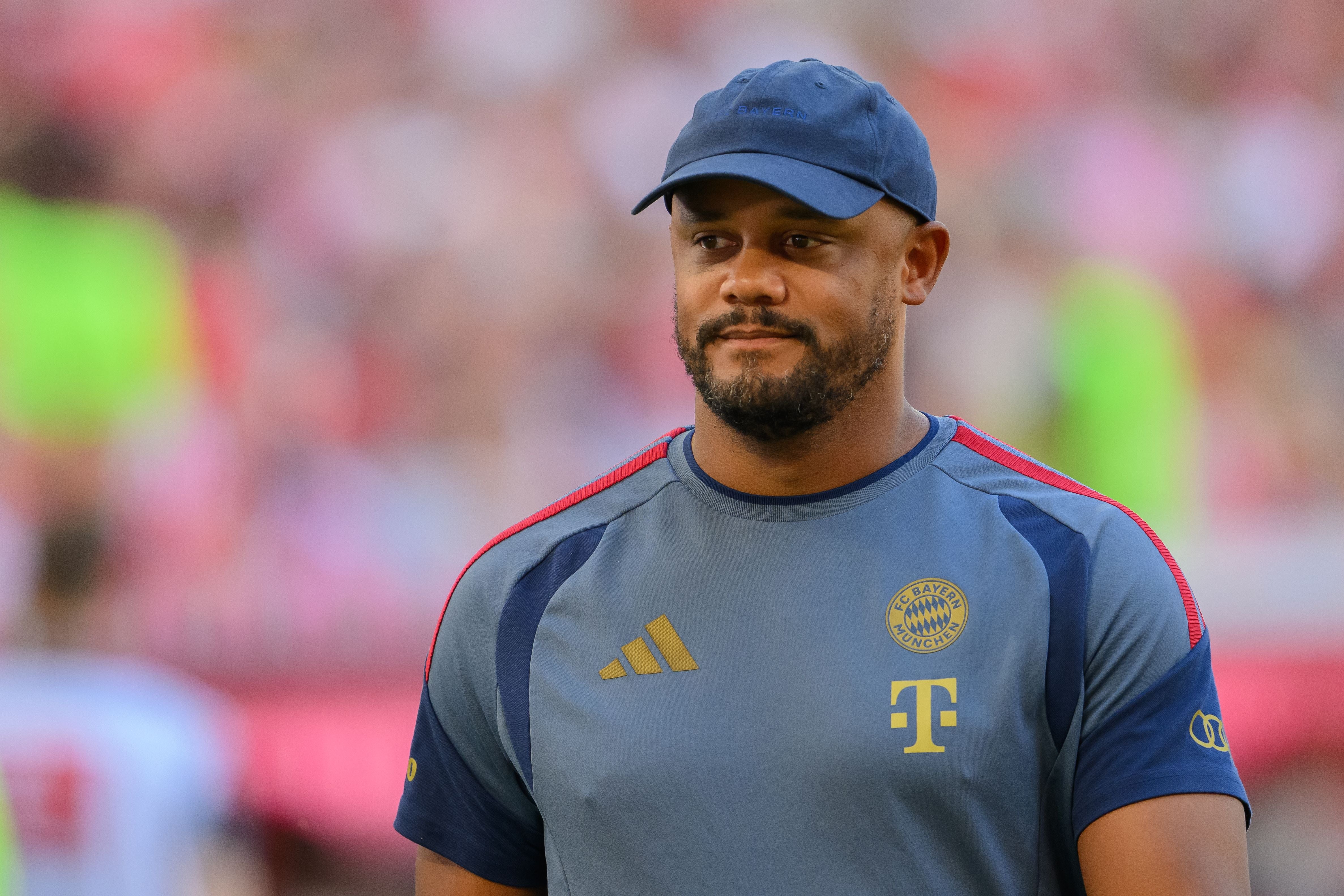 Ein Mann im FC Bayern Trainingsshirt und blauer Kappe steht im Stadion.