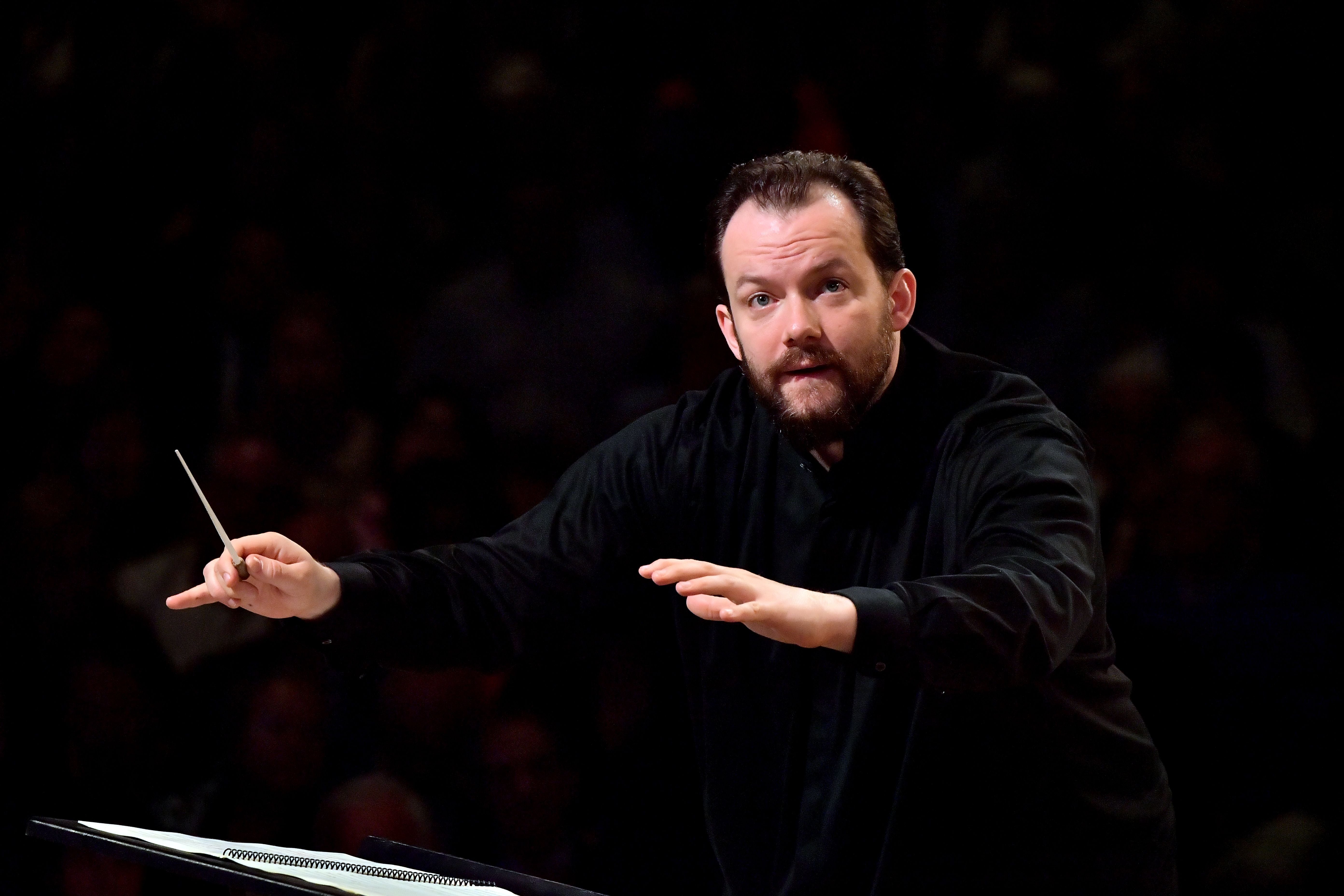 Ein Dirigent leitet ein Orchester mit Taktstock bei einem Konzert.