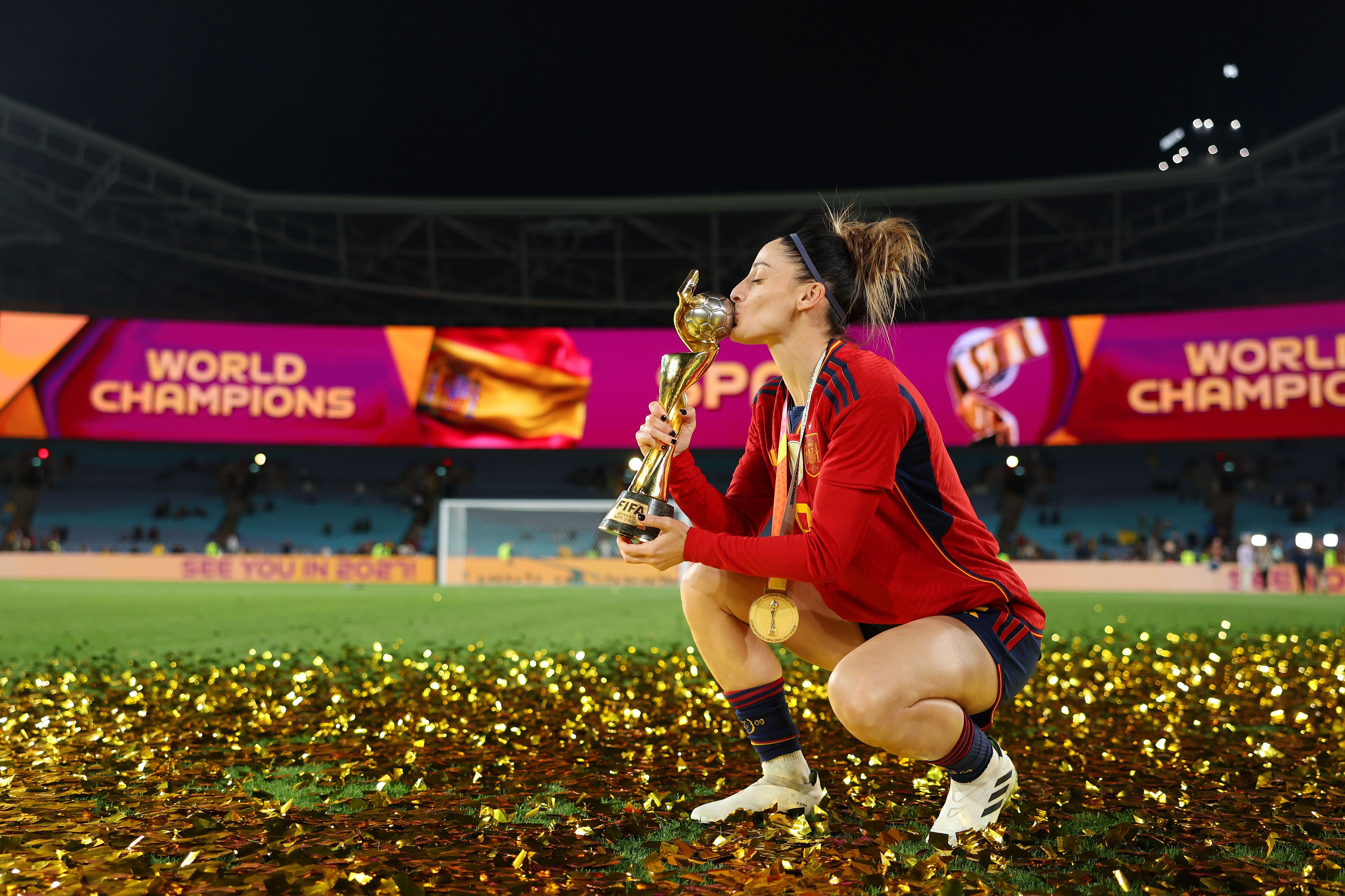 Eine spanische Fußballerin küsst den WM-Pokal vor einer Bühne mit "World Champions".