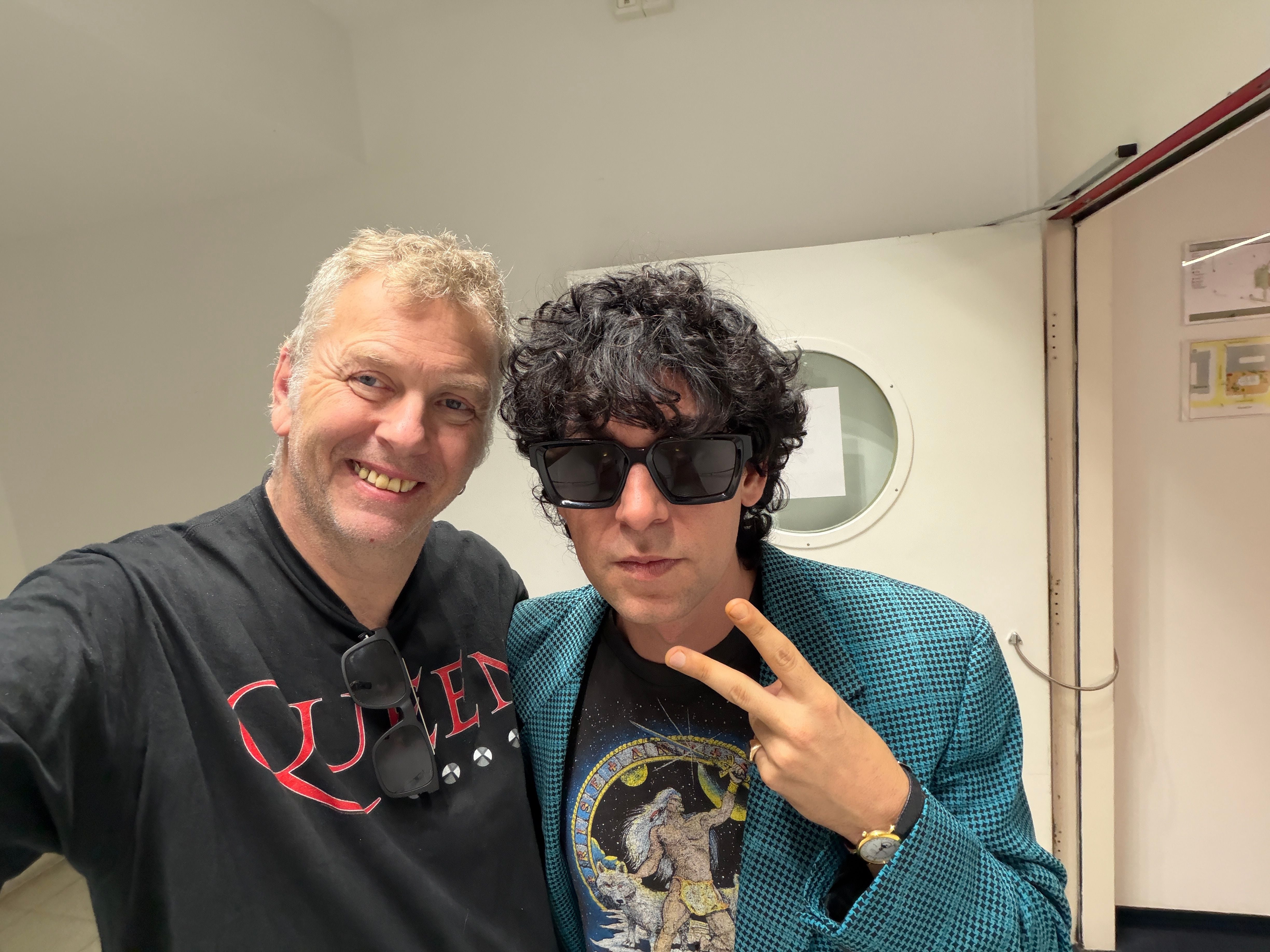 Zwei Männer posieren für ein Selfie, einer zeigt ein Peace-Zeichen, beide lächeln.