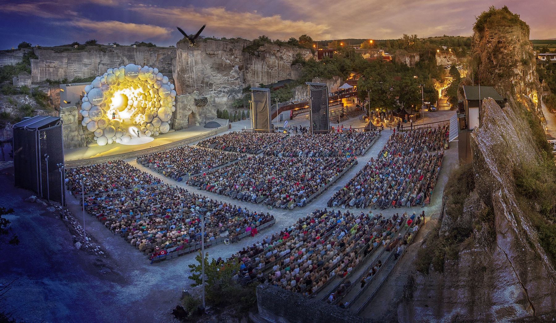 Großes Freiluft-Opernfestival im beleuchteten Steinbruch mit vielen Zuschauern und imposanter Bühne.