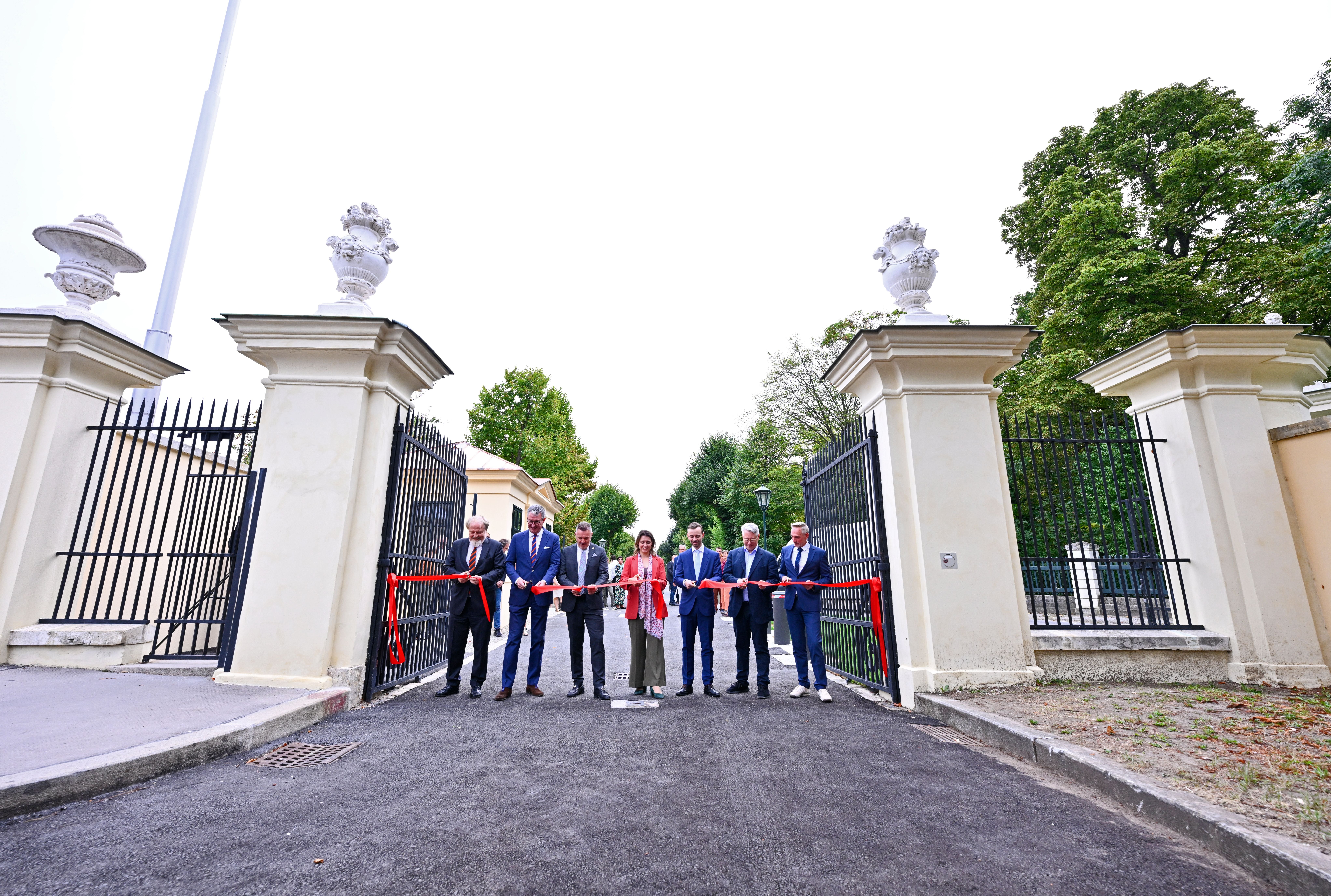 Menschen schneiden ein rotes Band bei der Eröffnung des Engelstors am Schlosspark Schönbrunn.