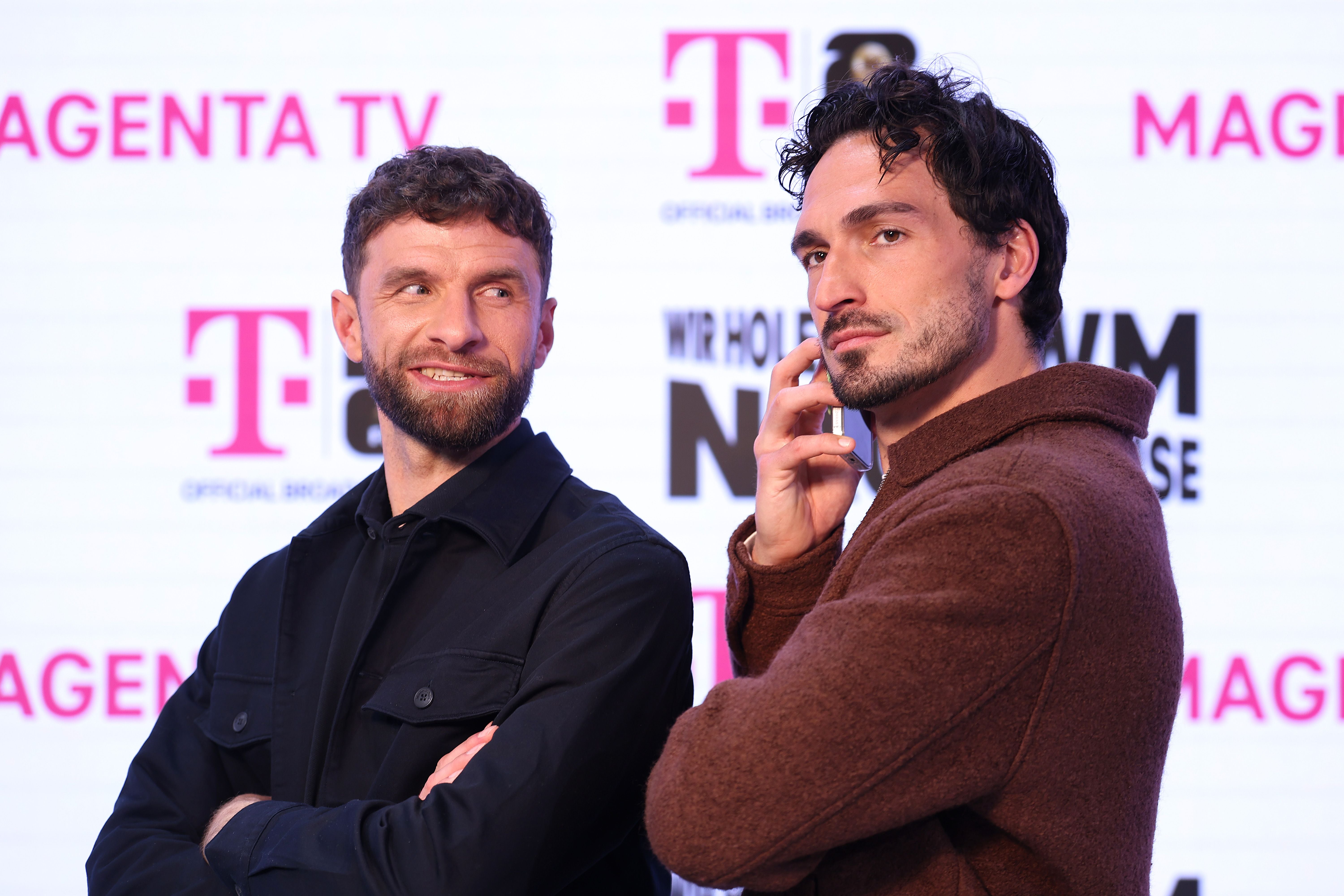 Zwei Männer posieren vor einem Hintergrund mit MagentaTV-Logos und lächeln in die Kamera.
