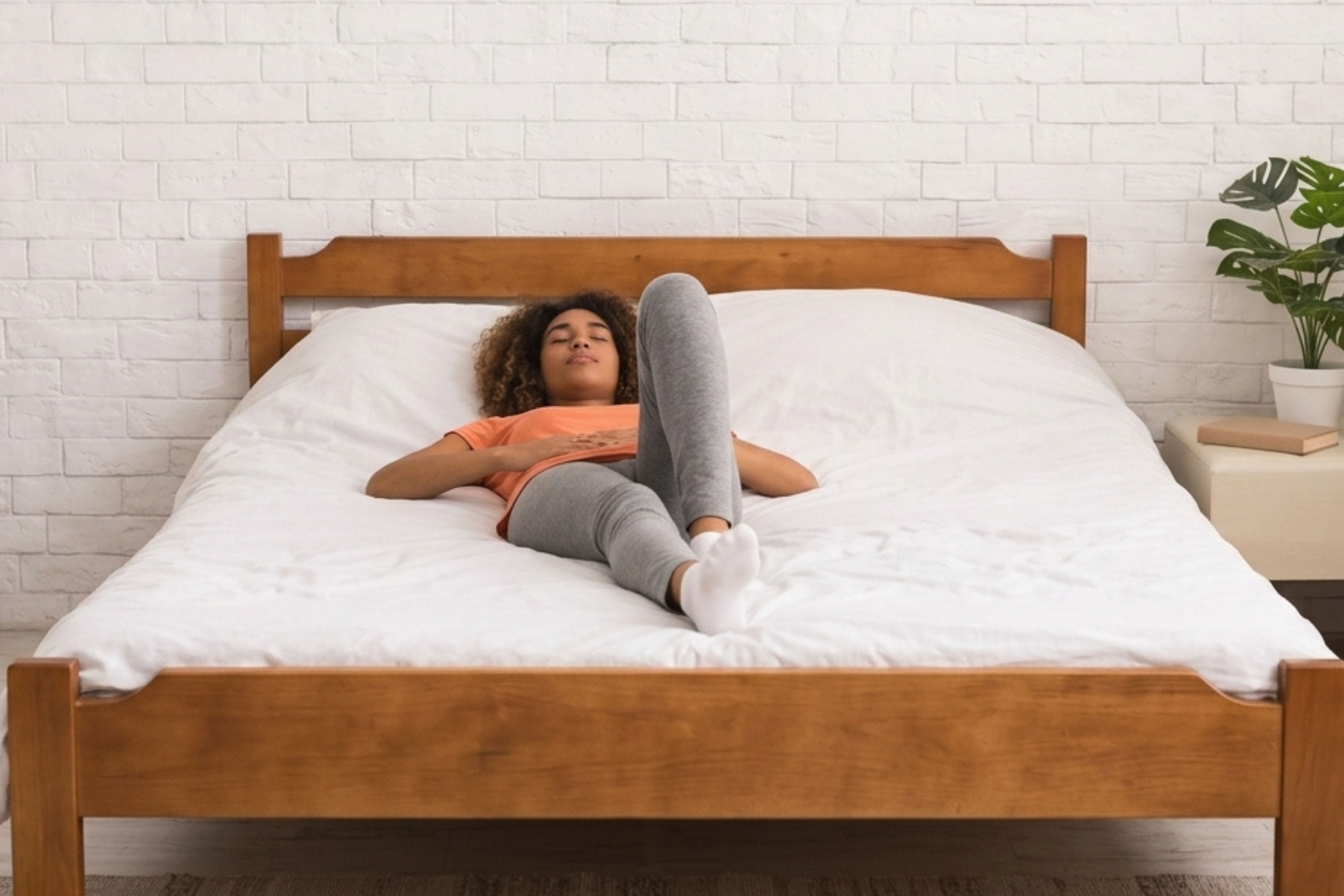 Eine junge Frau liegt entspannt auf einem großen Bett mit weißer Bettwäsche.